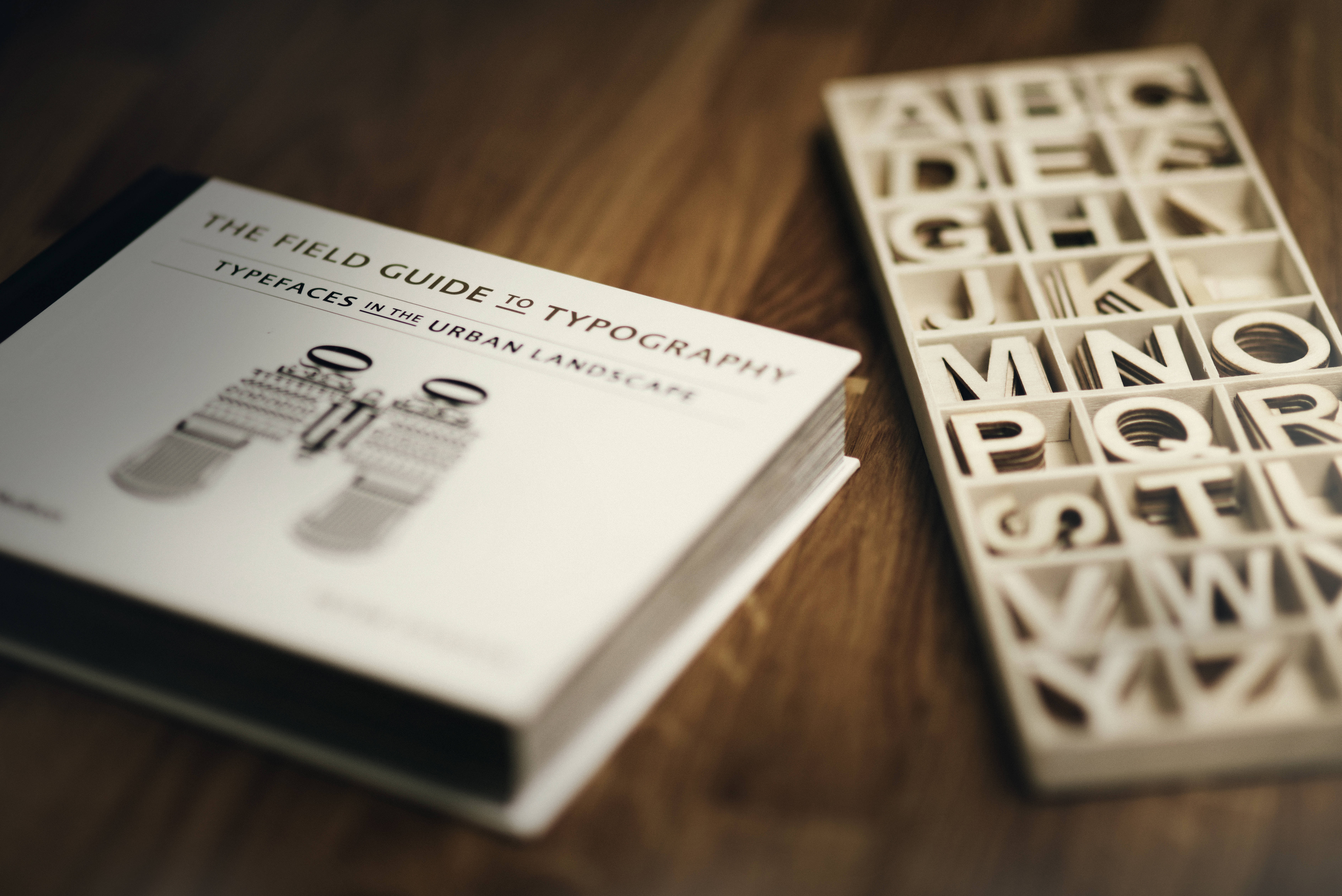 The Field Guide to Typography, 3D letterpress block, warm wooden surface, 5K Desktop Wallpaper