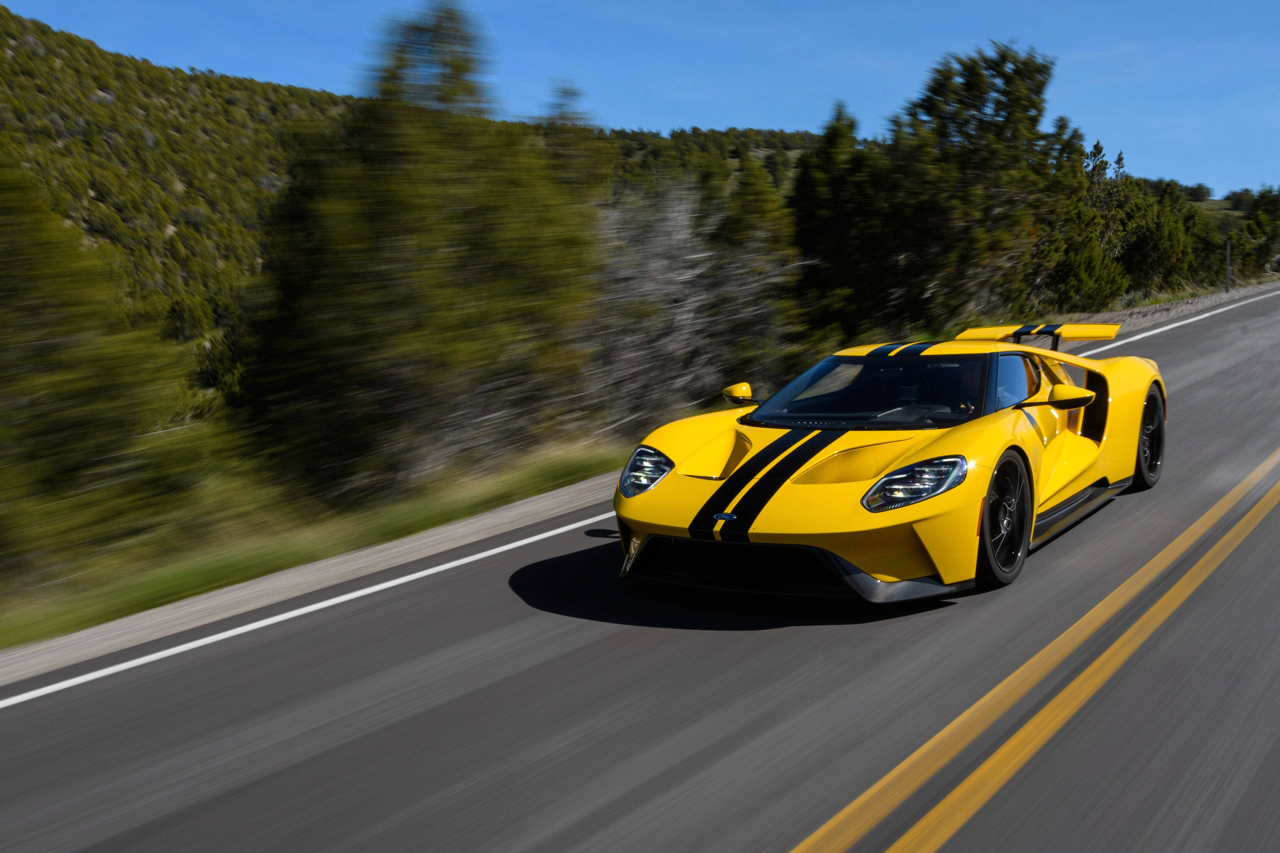 yellow Ford GT, winding mountain road, blurred green trees, 4K Desktop Wallpaper
