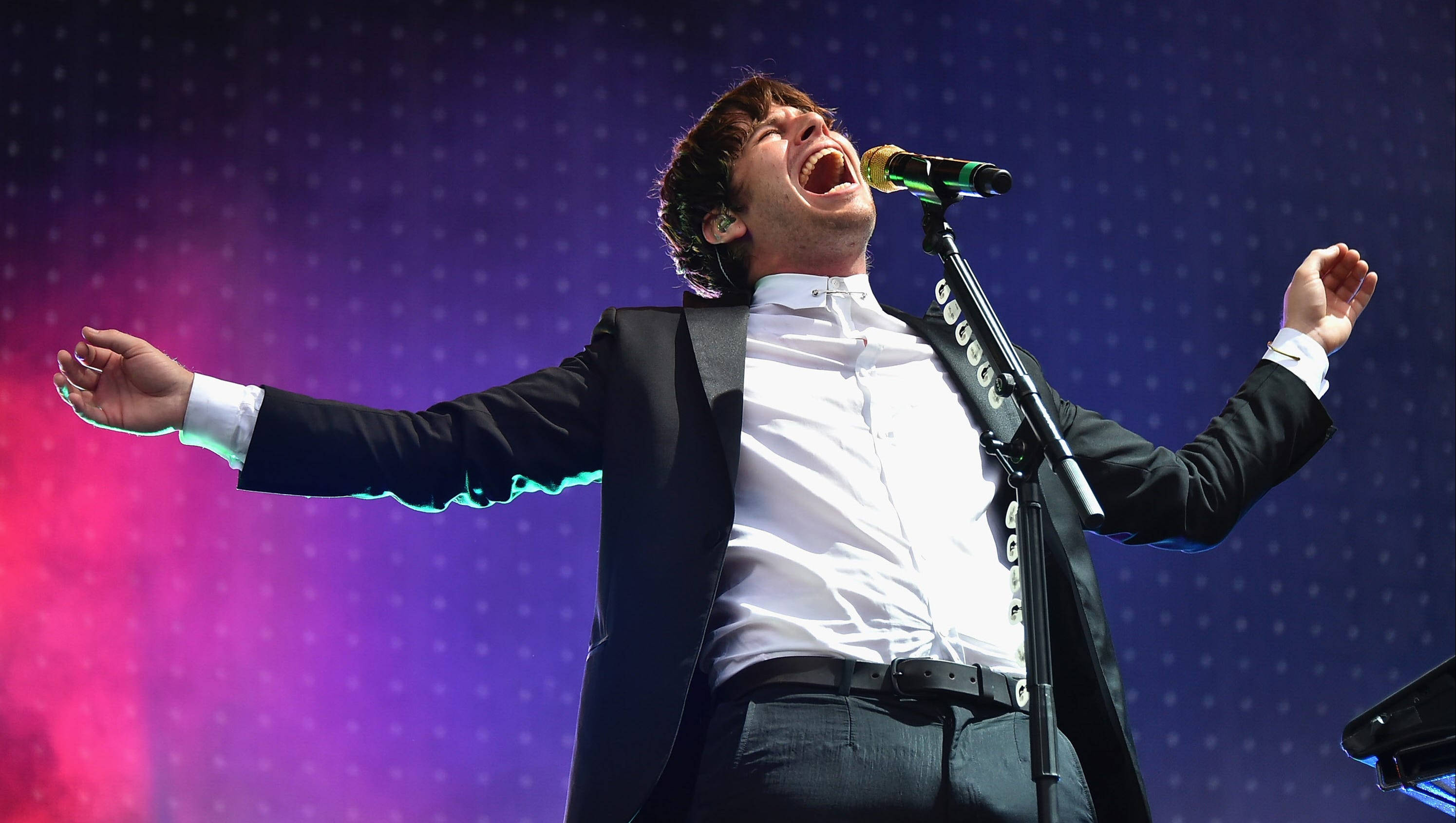 Foster the People, black suit, vibrant purple and pink dotted stage backdrop, 2K Desktop Wallpaper