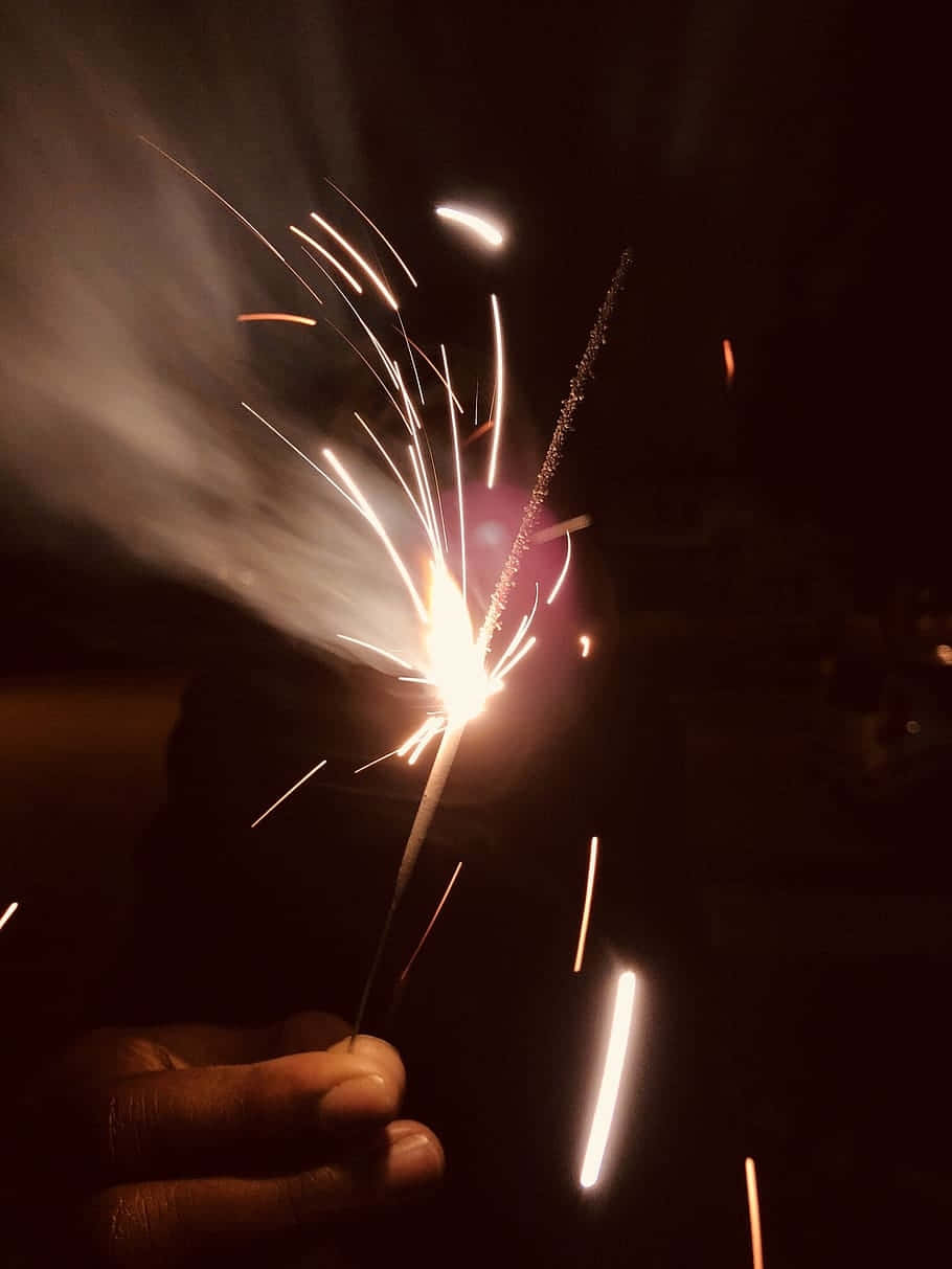 nighttime sparkler celebration, lit sparkler, bright white and orange sparks, SD Phone Wallpaper
