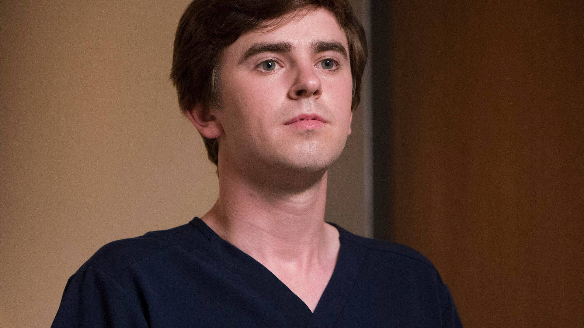 Freddie Highmore, dark blue scrubs, serious expression, Full HD Desktop Wallpaper