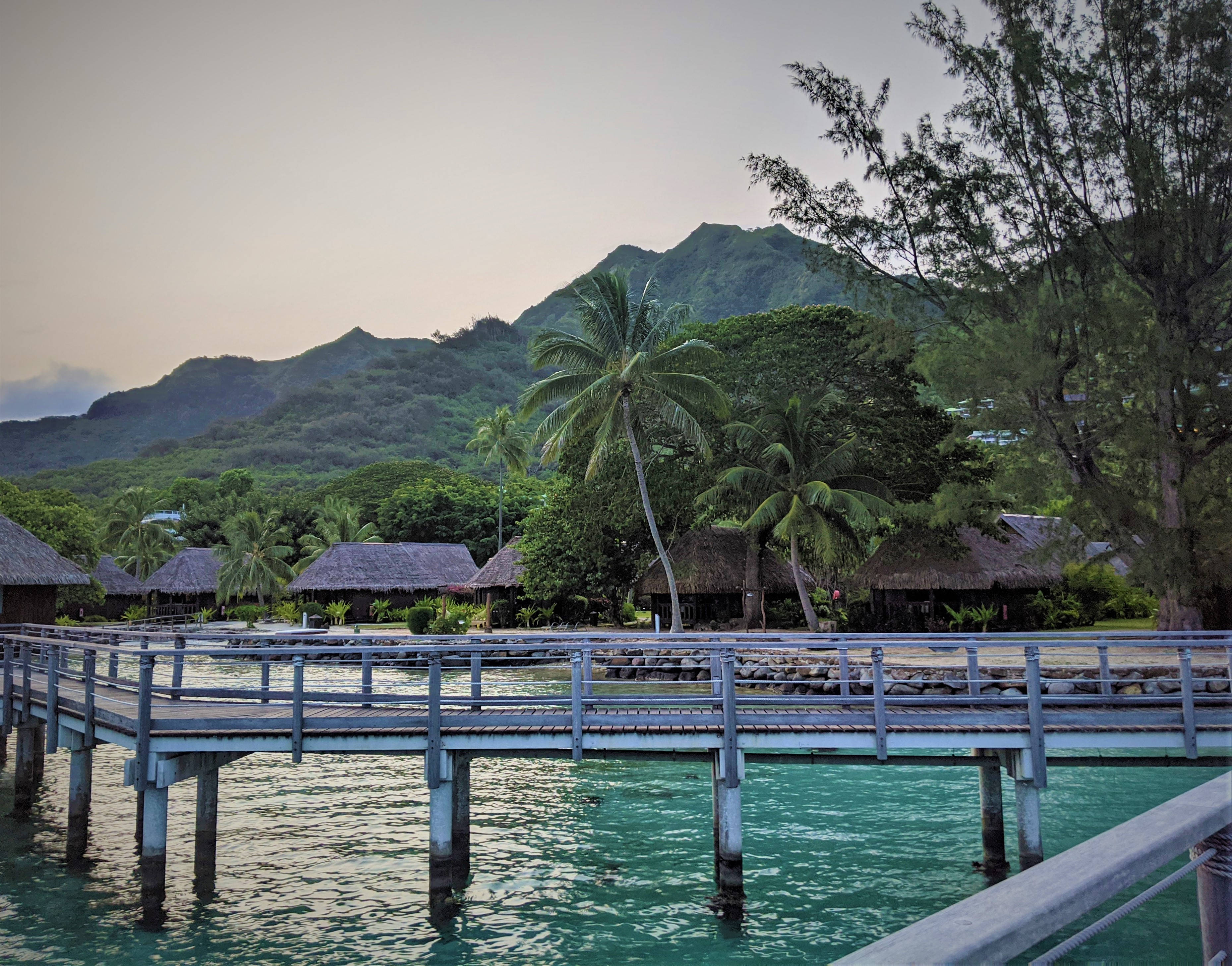 wooden bridge, turquoise water, thatched-roof huts, 2K Desktop Wallpaper