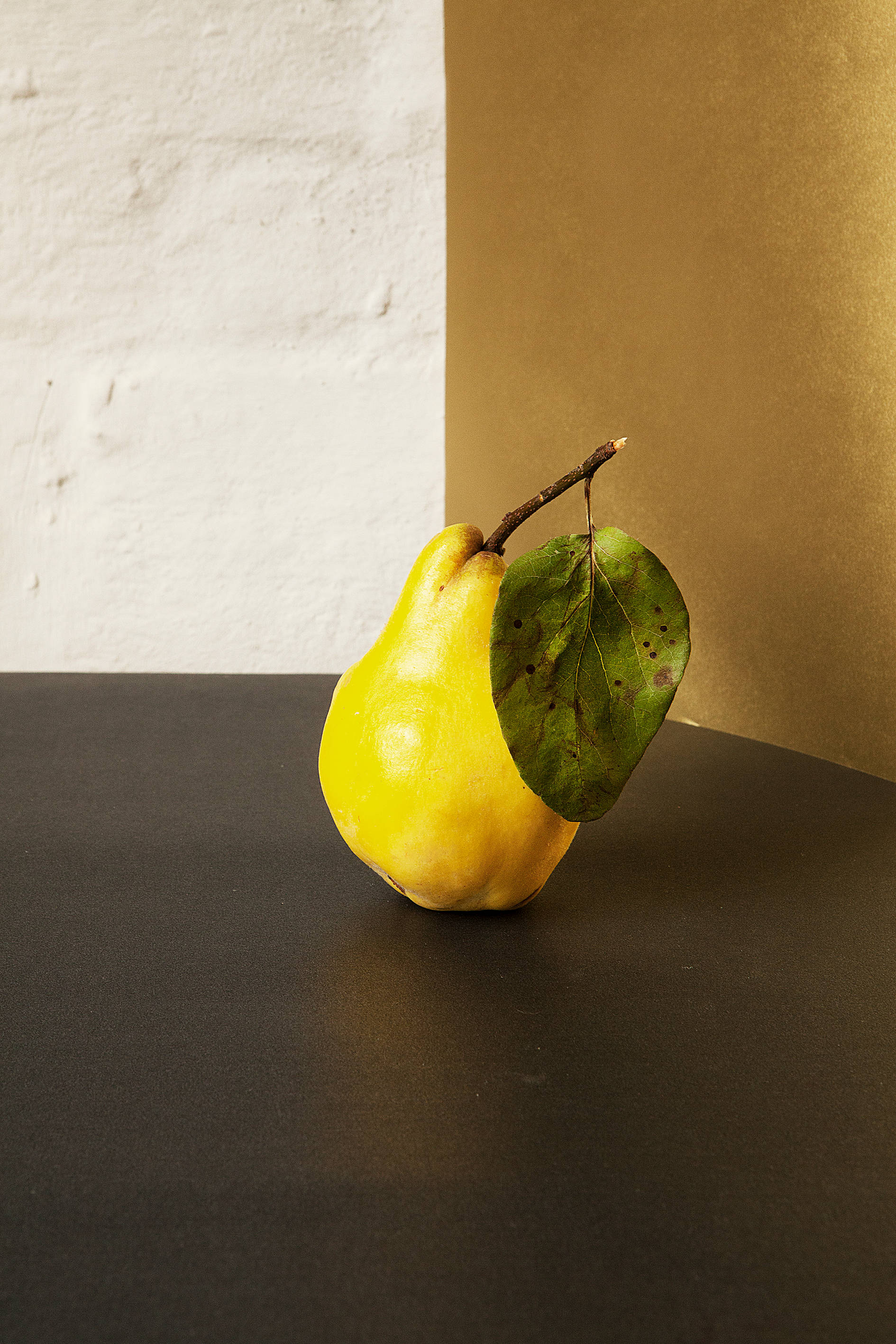 ripe yellow pear, spotted green leaf, dark surface, 2K Phone Wallpaper