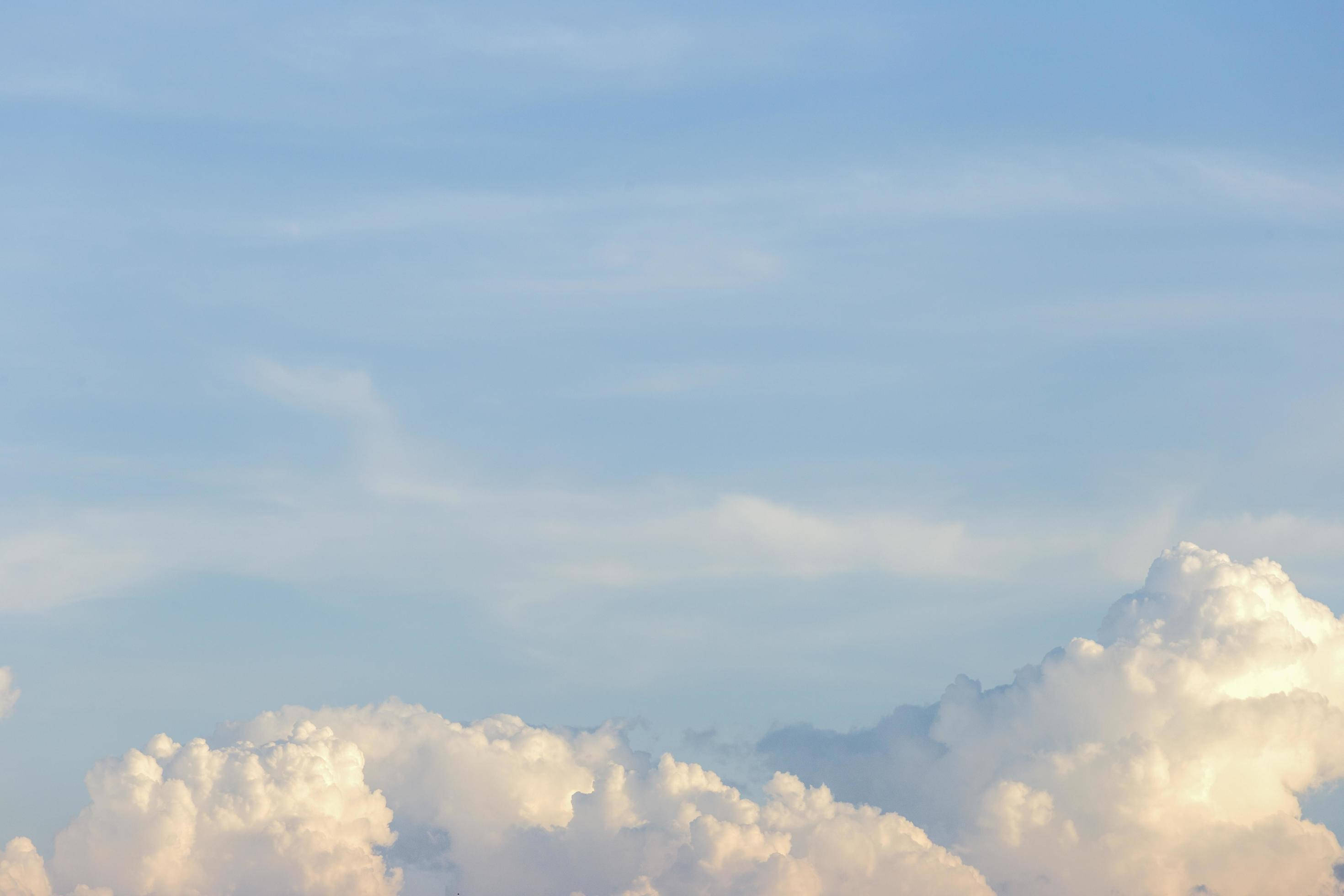 soft white clouds, serene blue sky, gentle golden sunlight, 2K Desktop Wallpaper
