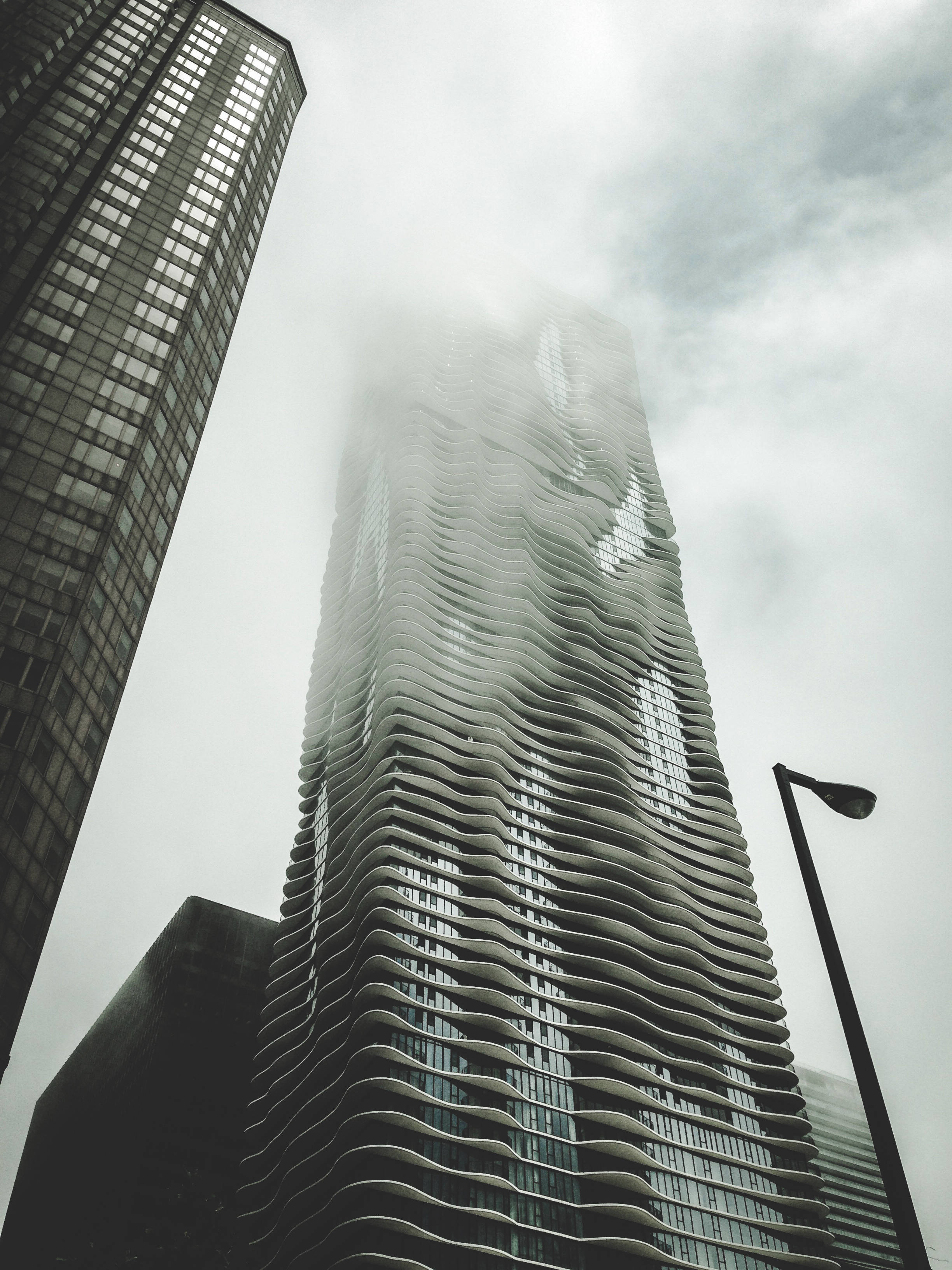 monochrome futuristic city buildings, mist-shrouded modern skyscraper, wavy balconies, 2K Phone Wallpaper