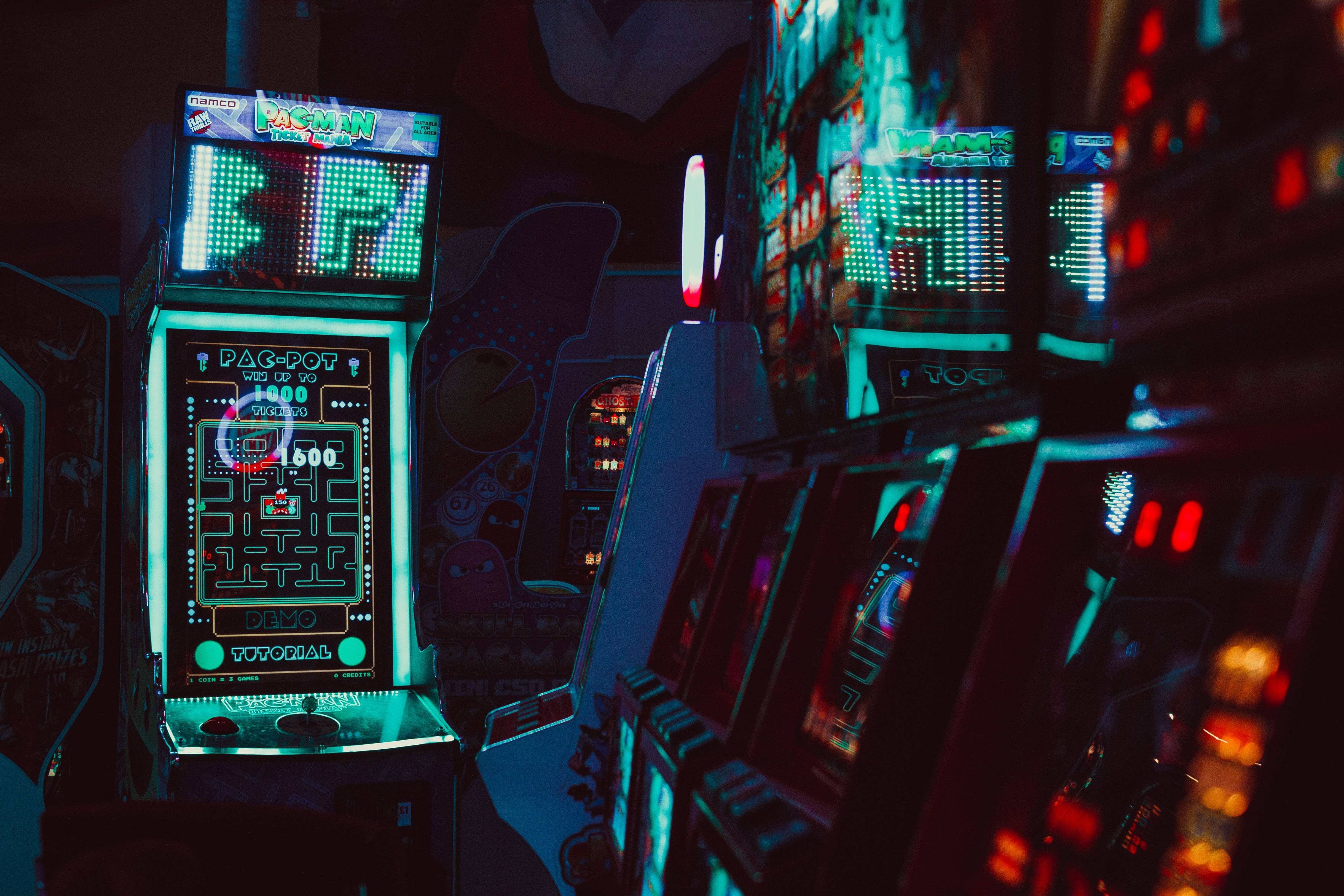 neon-lit arcade machines, glowing Pac-Man cabinets, dimly lit gaming hall, 4K Desktop Wallpaper