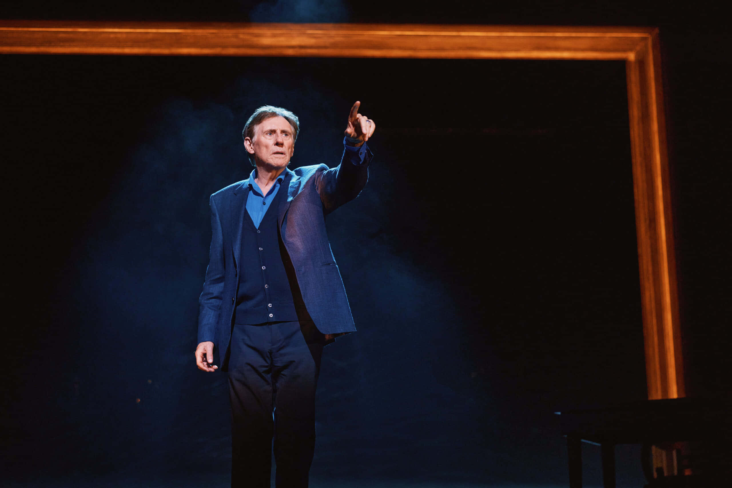 Gabriel Byrne, blue suit, dimly lit stage, 2K Desktop Wallpaper
