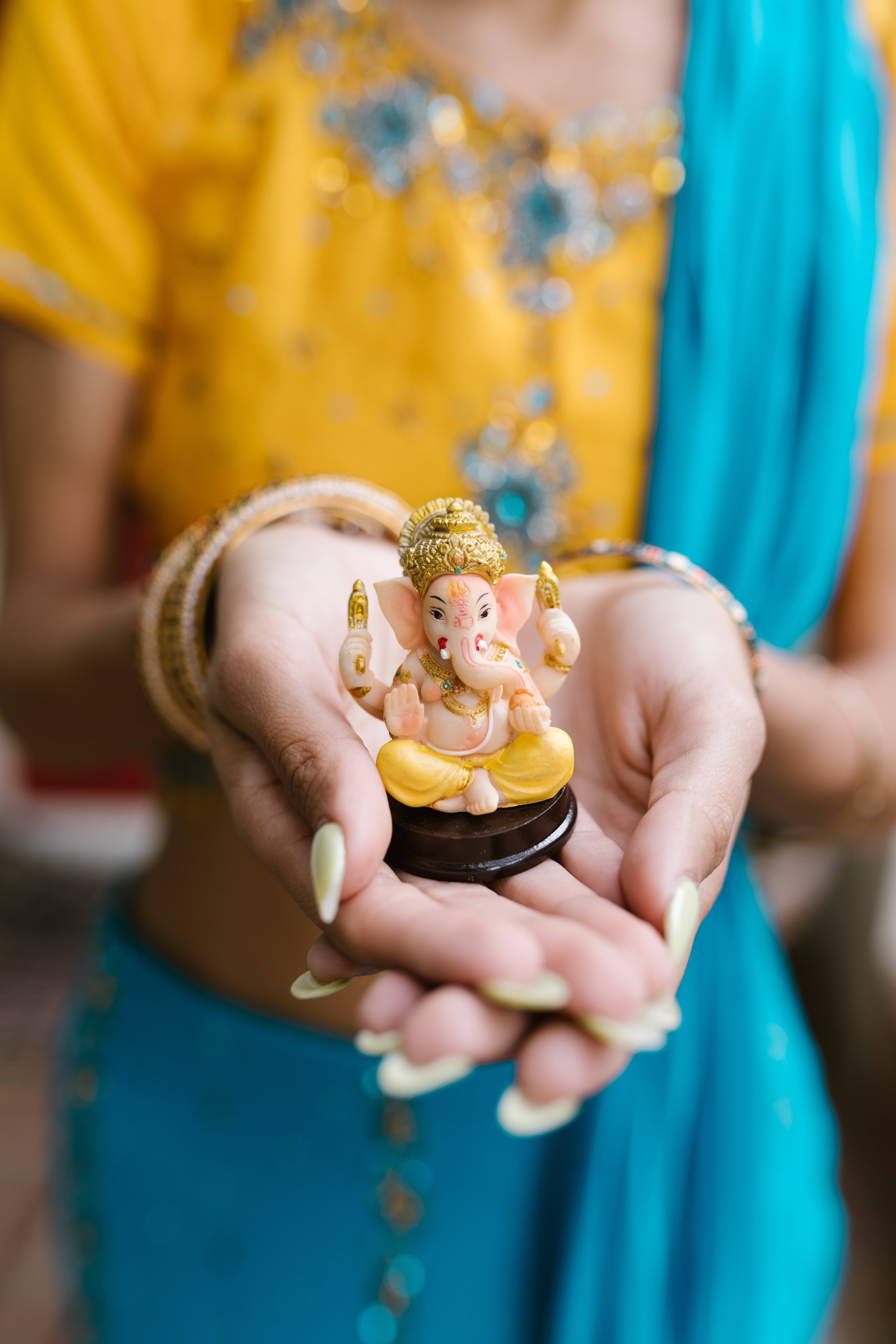Ganesh, golden Ganesha figurine, vibrant yellow and blue traditional attire, 5K Phone Wallpaper