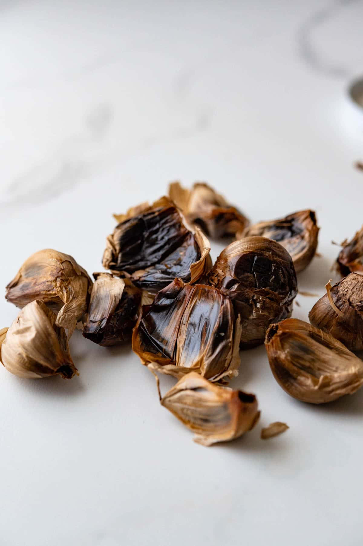 black garlic, charred skins, clean white marble surface, HD Phone Wallpaper