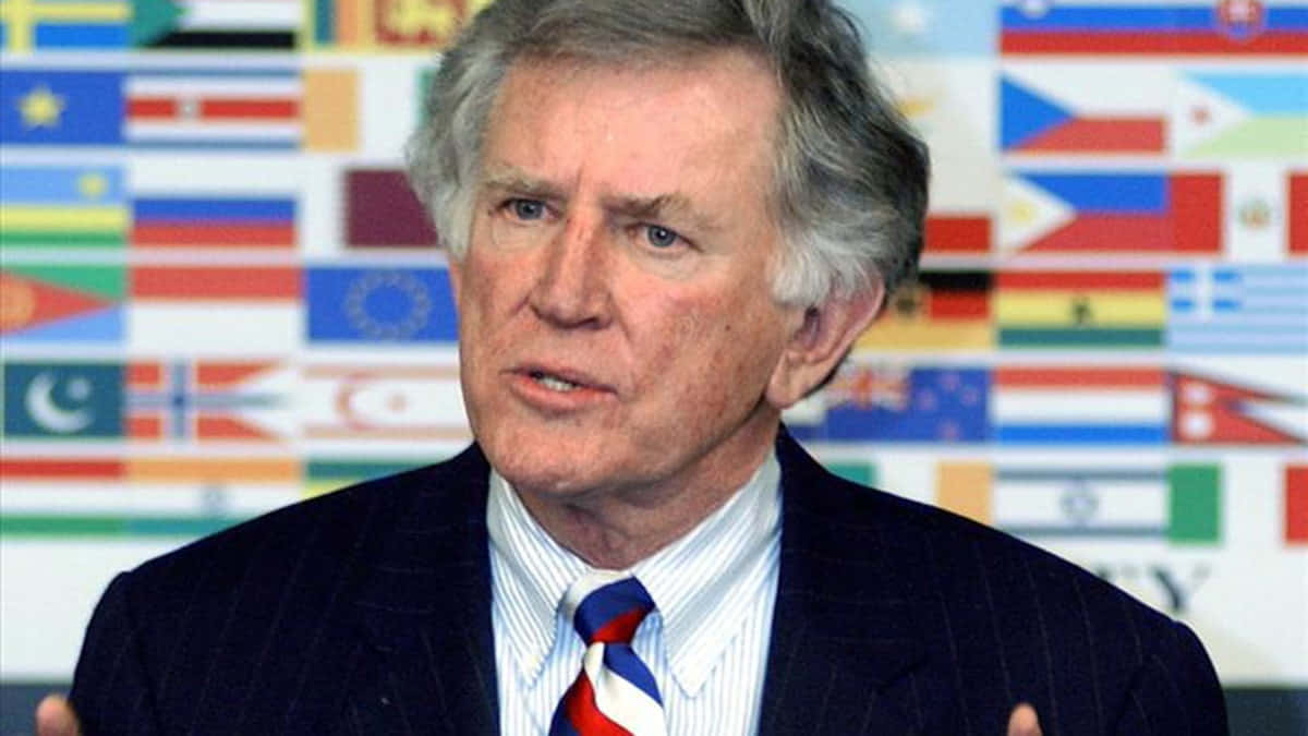 Gary Hart, suit and tie, backdrop of international flags, SD Desktop Wallpaper