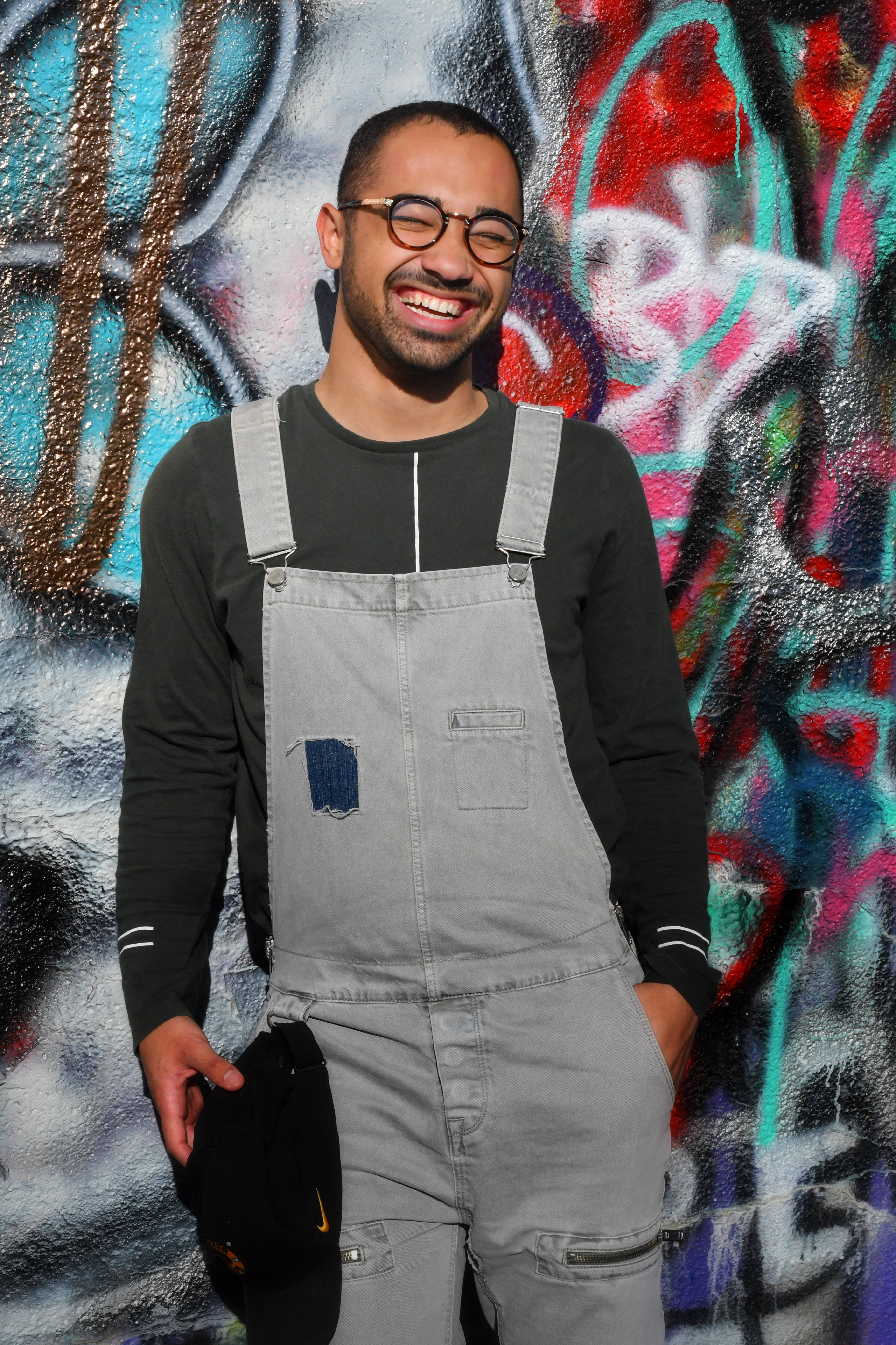gray overalls, glasses, vibrant graffiti-covered wall, 5K Phone Wallpaper