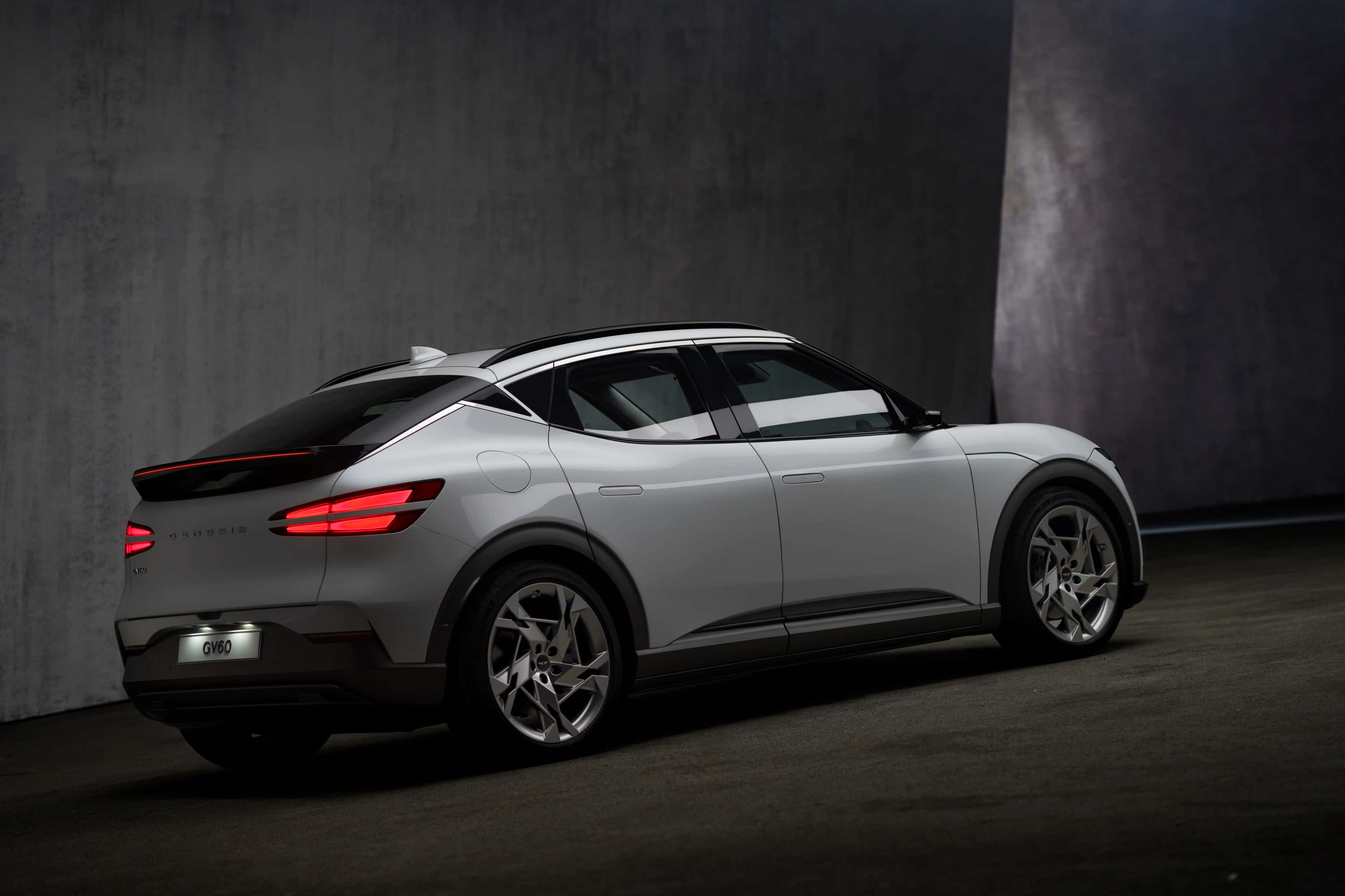 Genesis GV60, sleek silver electric SUV, glowing red taillights, 2K Desktop Wallpaper