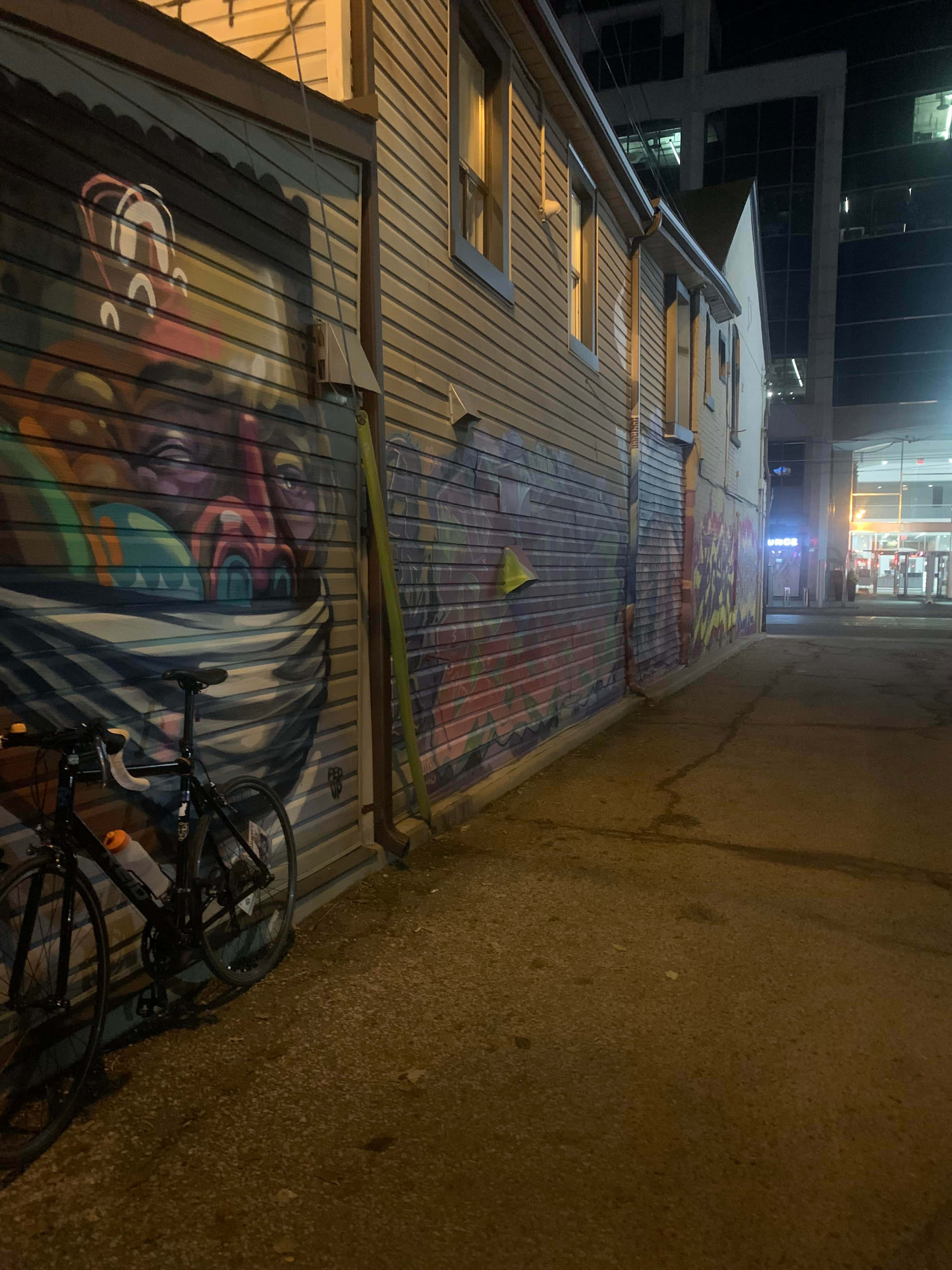 Ghetto Hood, graffiti-covered alley wall, city lights, 4K Phone Wallpaper