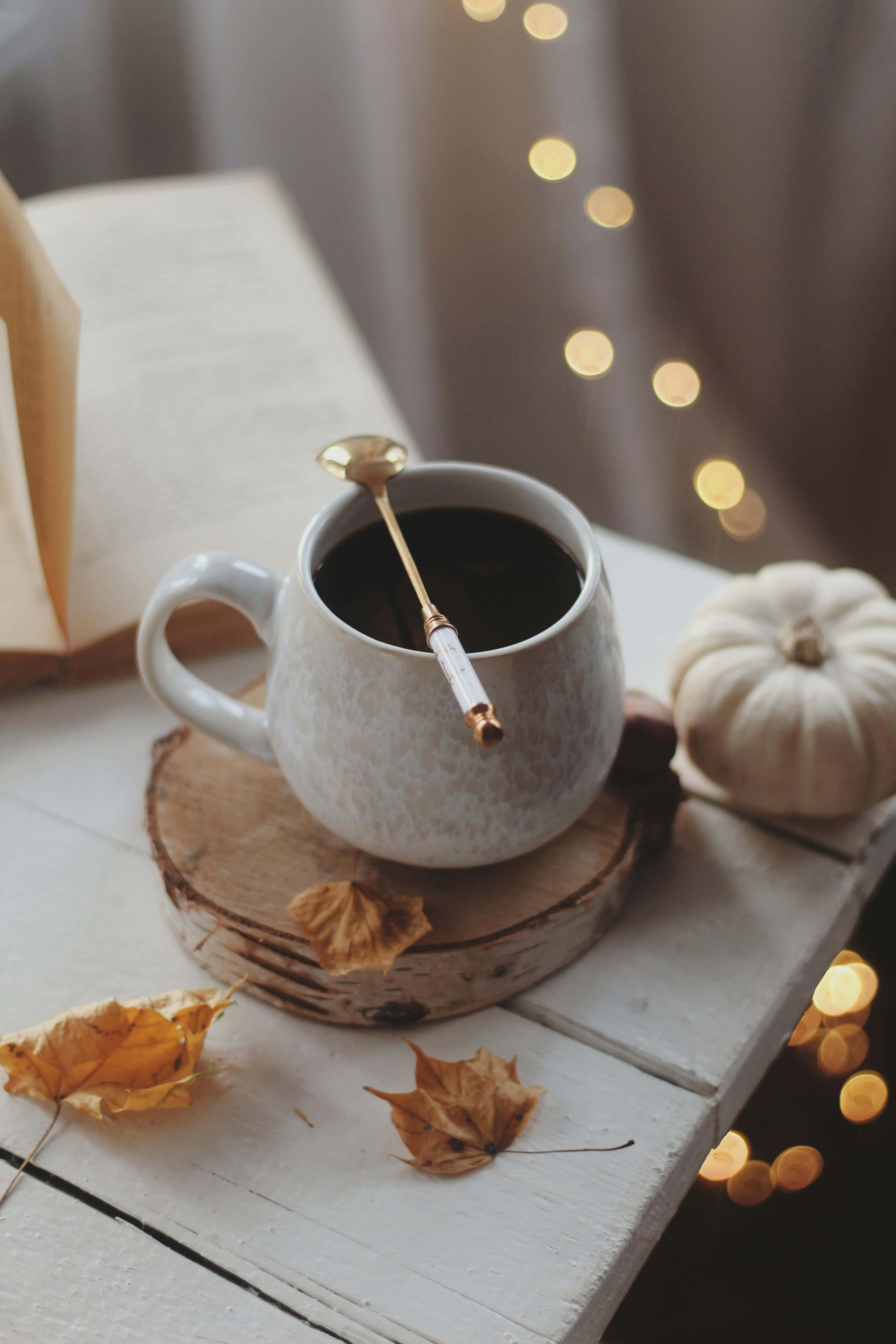 cozy autumn scene, ceramic mug of coffee, wooden coaster, 5K Phone Wallpaper