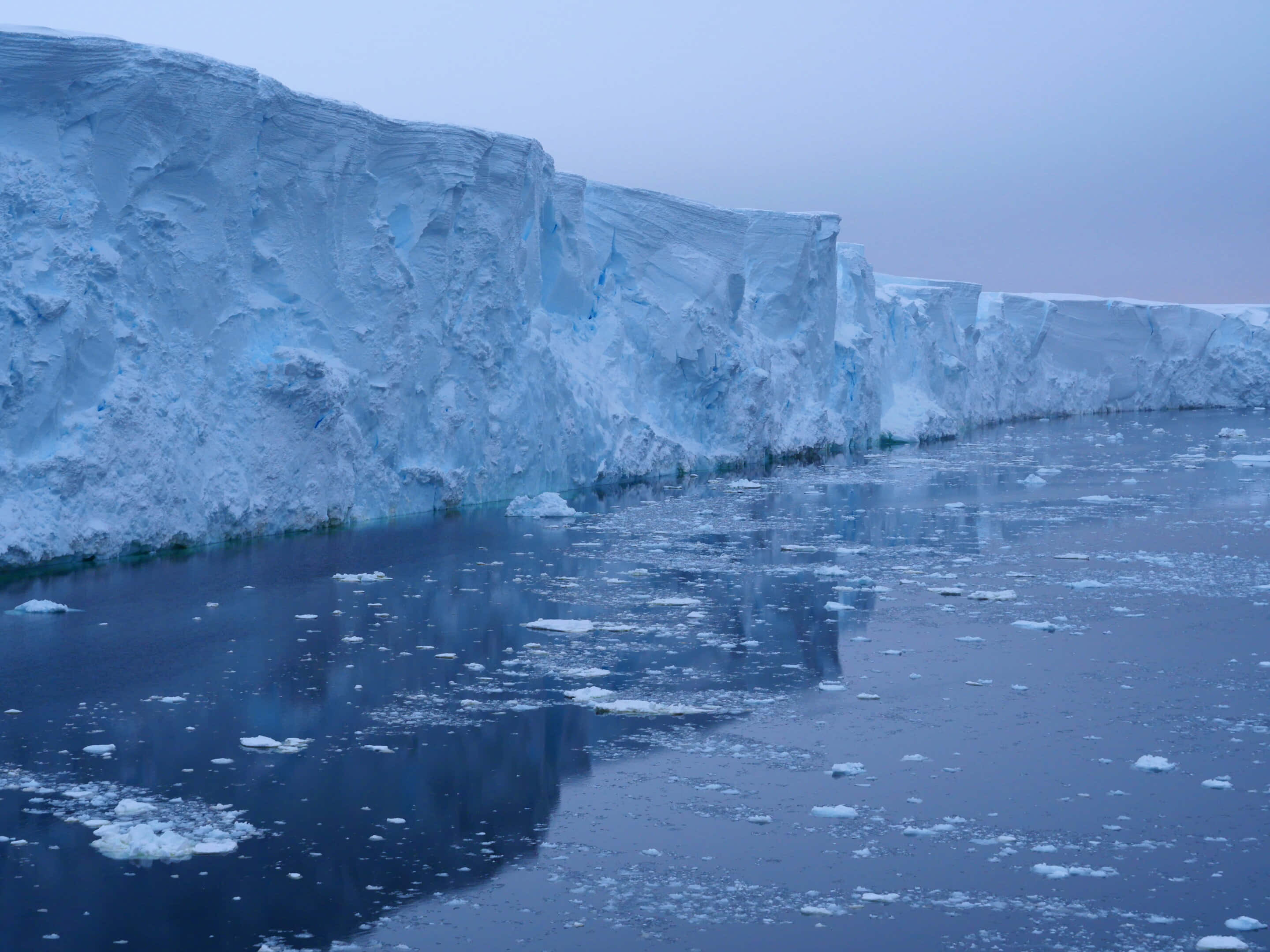 Glacial, blue-white ice cliffs, dark blue water, 2K Desktop Wallpaper
