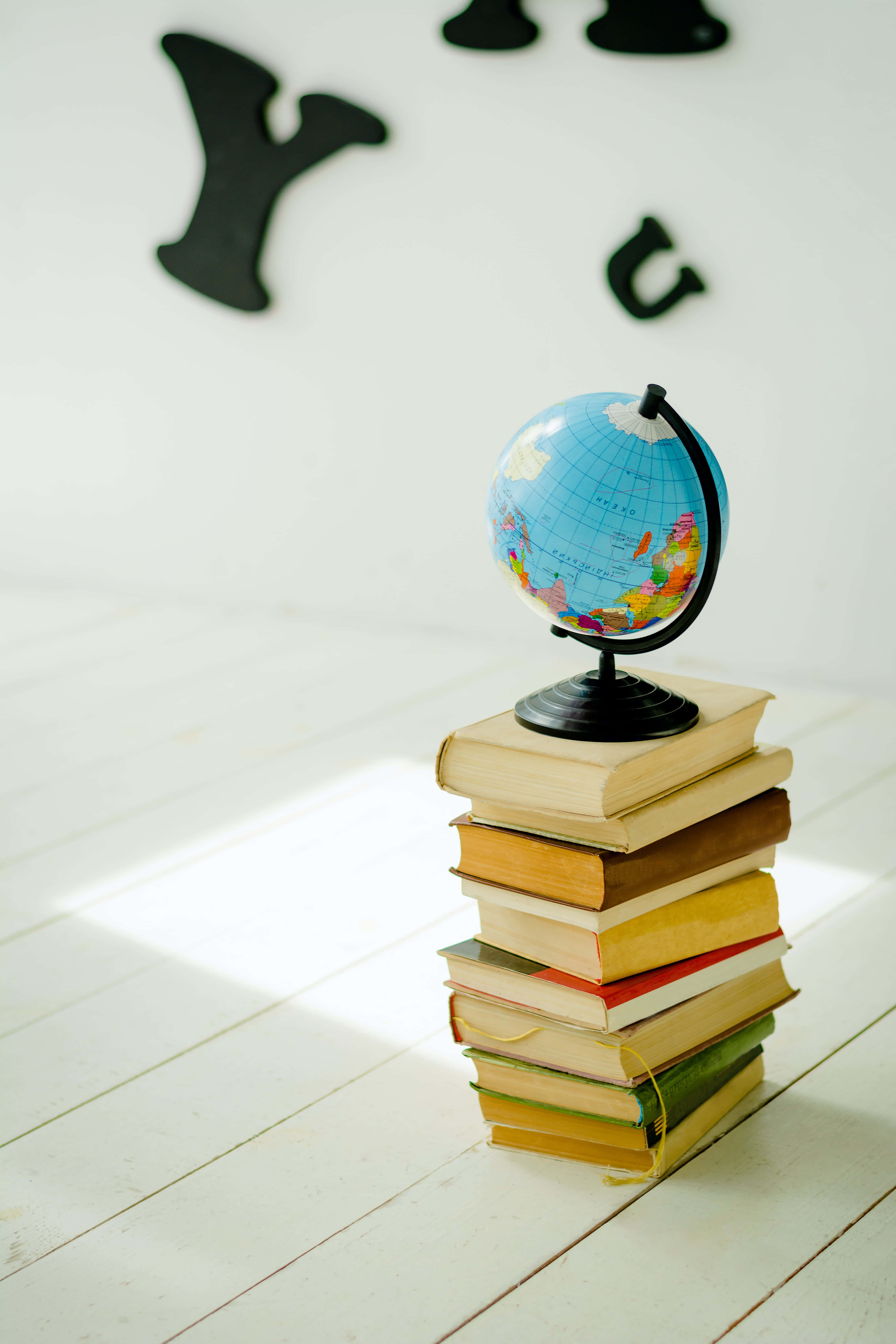 small globe map, stacked books, white wooden floor, 5K Phone Wallpaper