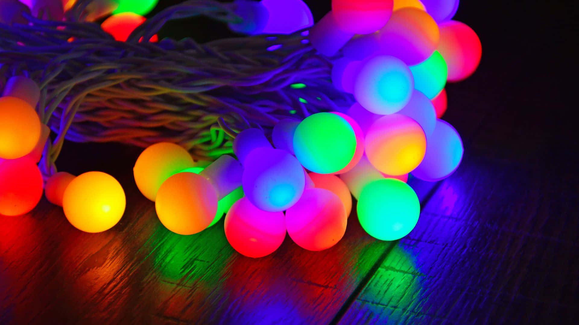 Glow In The Dark, rainbow-colored string lights, dark wooden surface, Full HD Desktop Wallpaper
