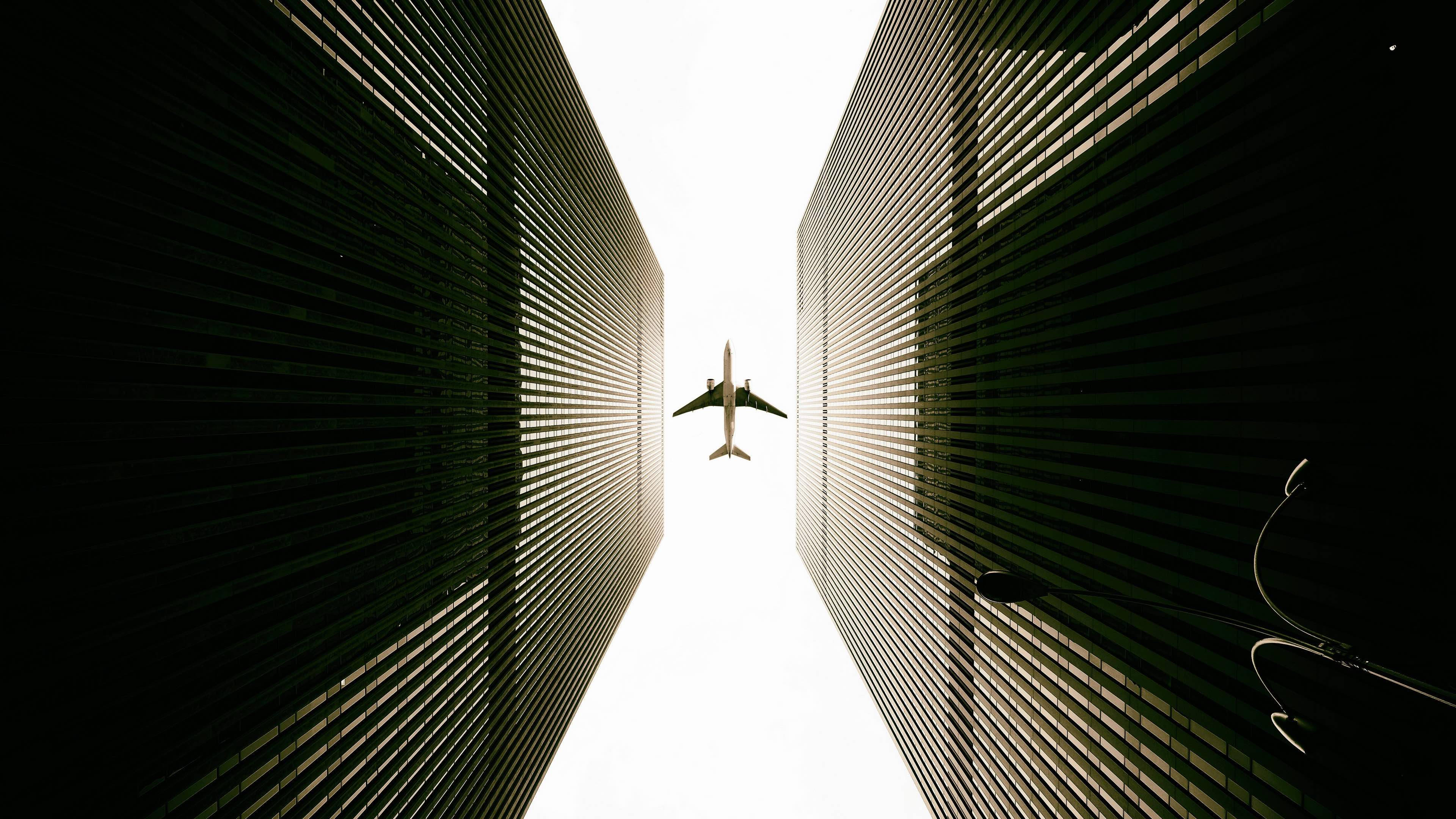 Google Flights, commercial airplane, towering dark green skyscrapers, 4K Desktop Wallpaper