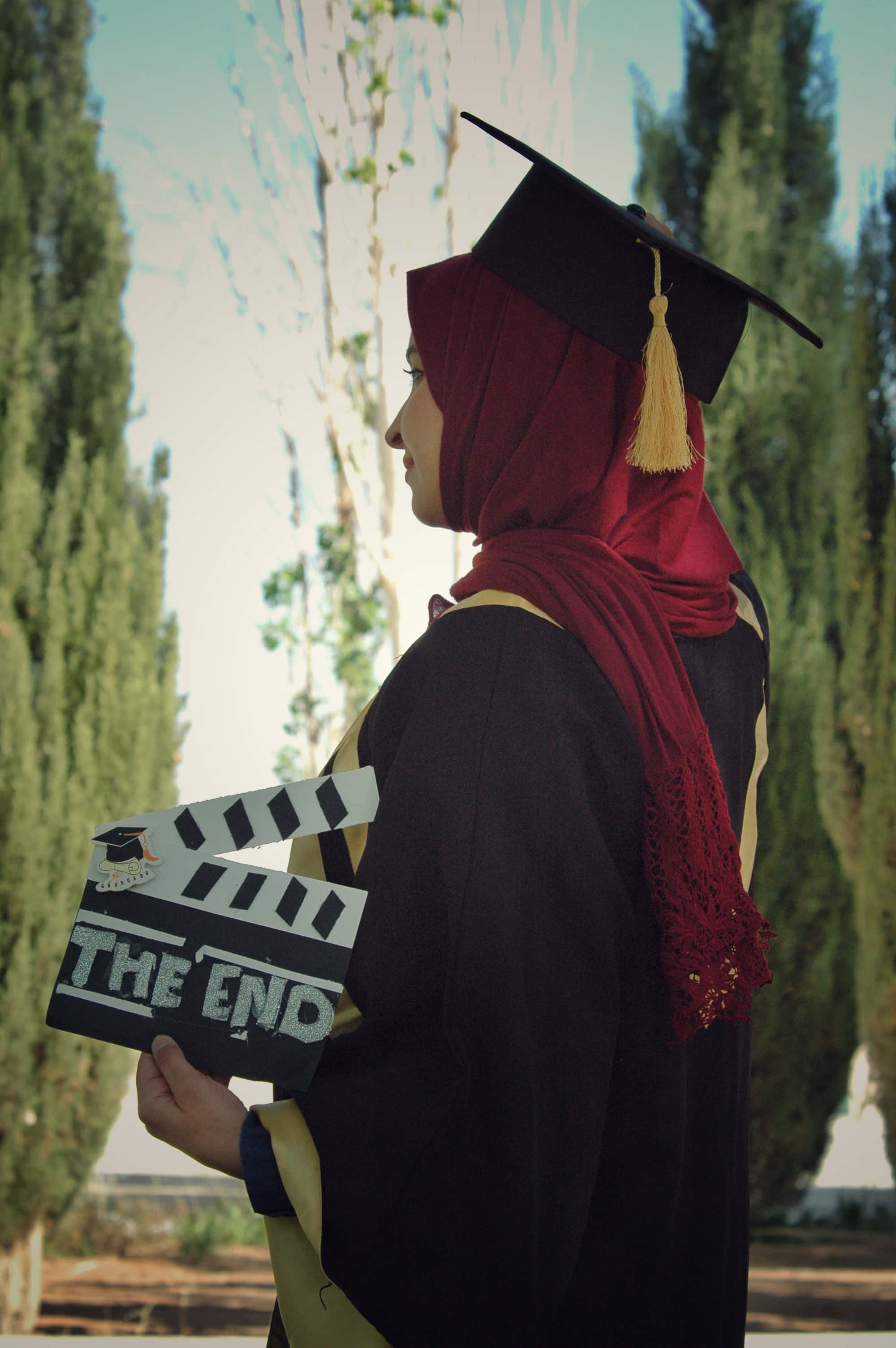black cap and gown, red hijab, clapperboard reading 'THE END', 2K Phone Wallpaper