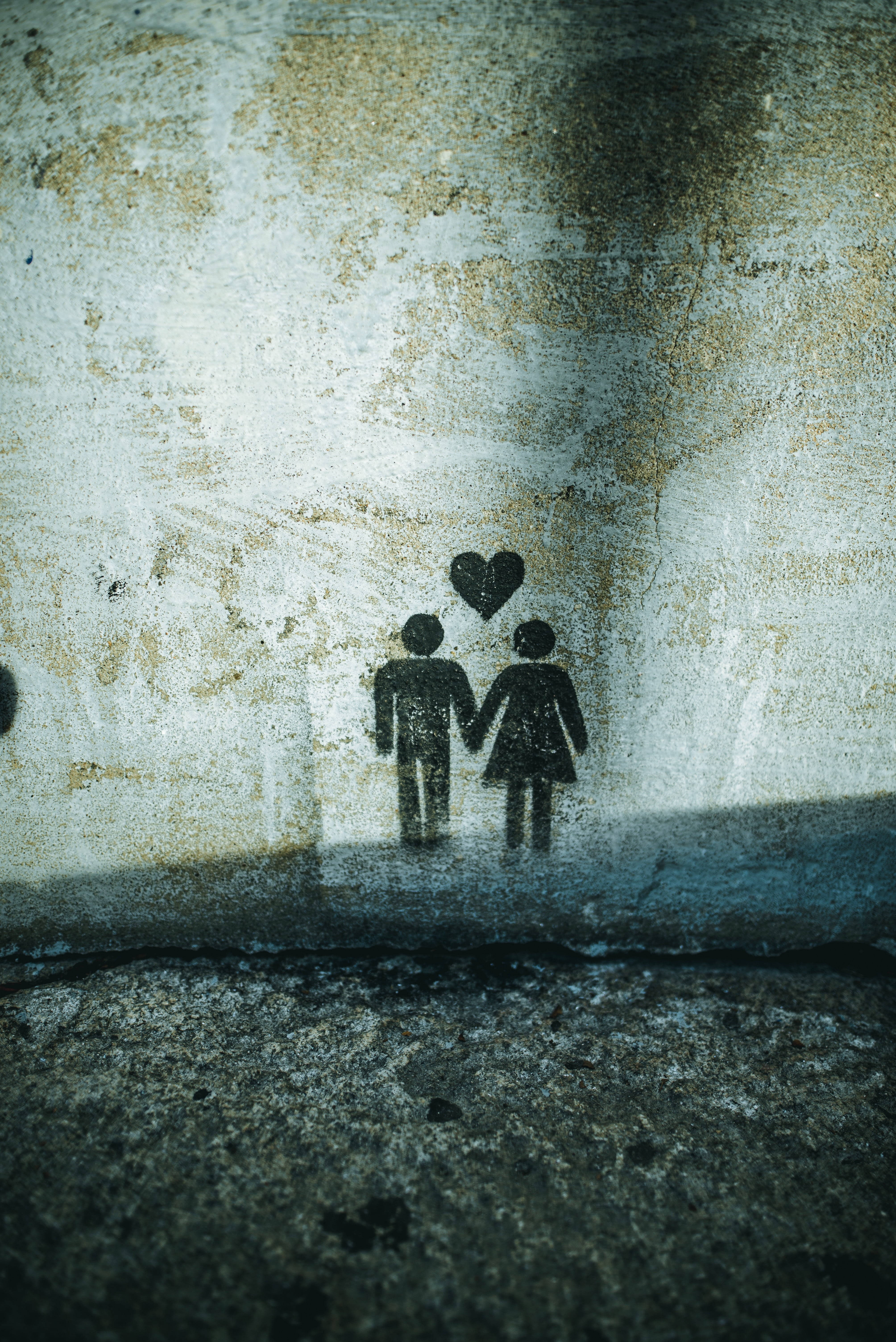 black silhouetted figures, heart above them, weathered concrete wall, 5K Phone Wallpaper
