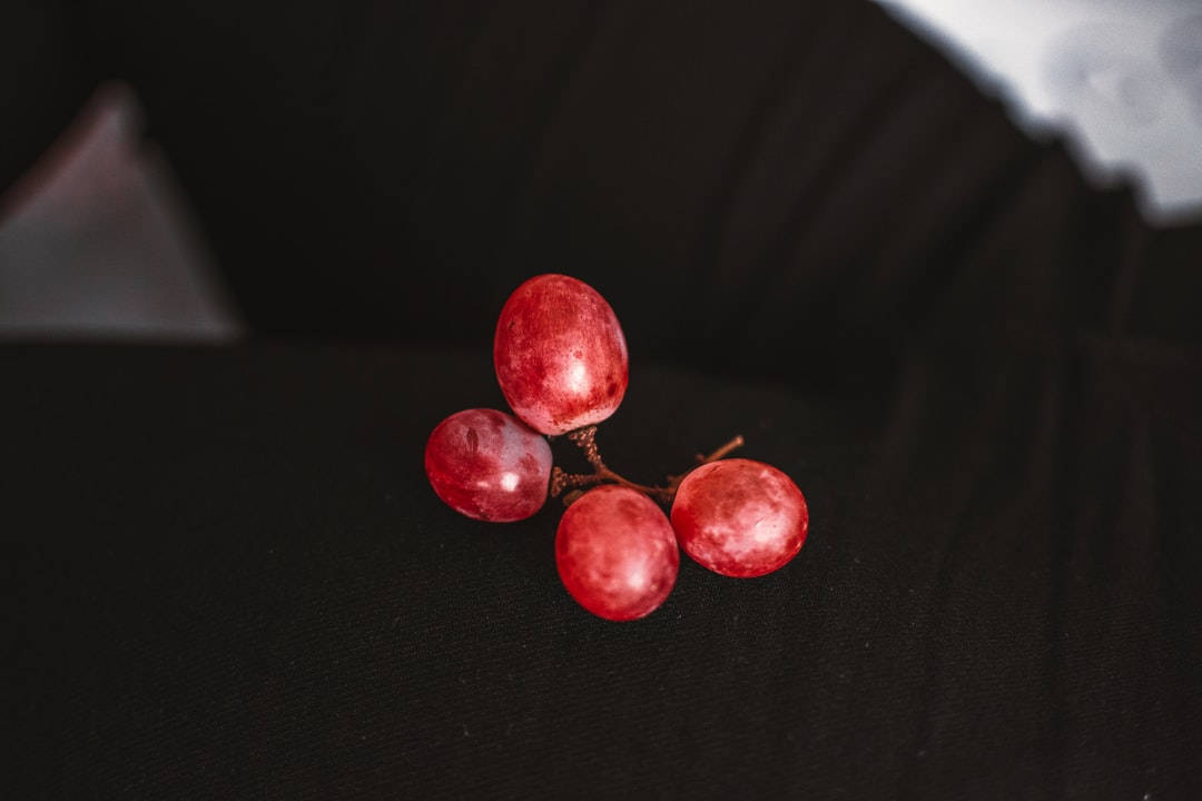 four red grapes, dark textured surface, soft lighting, SD Desktop Wallpaper