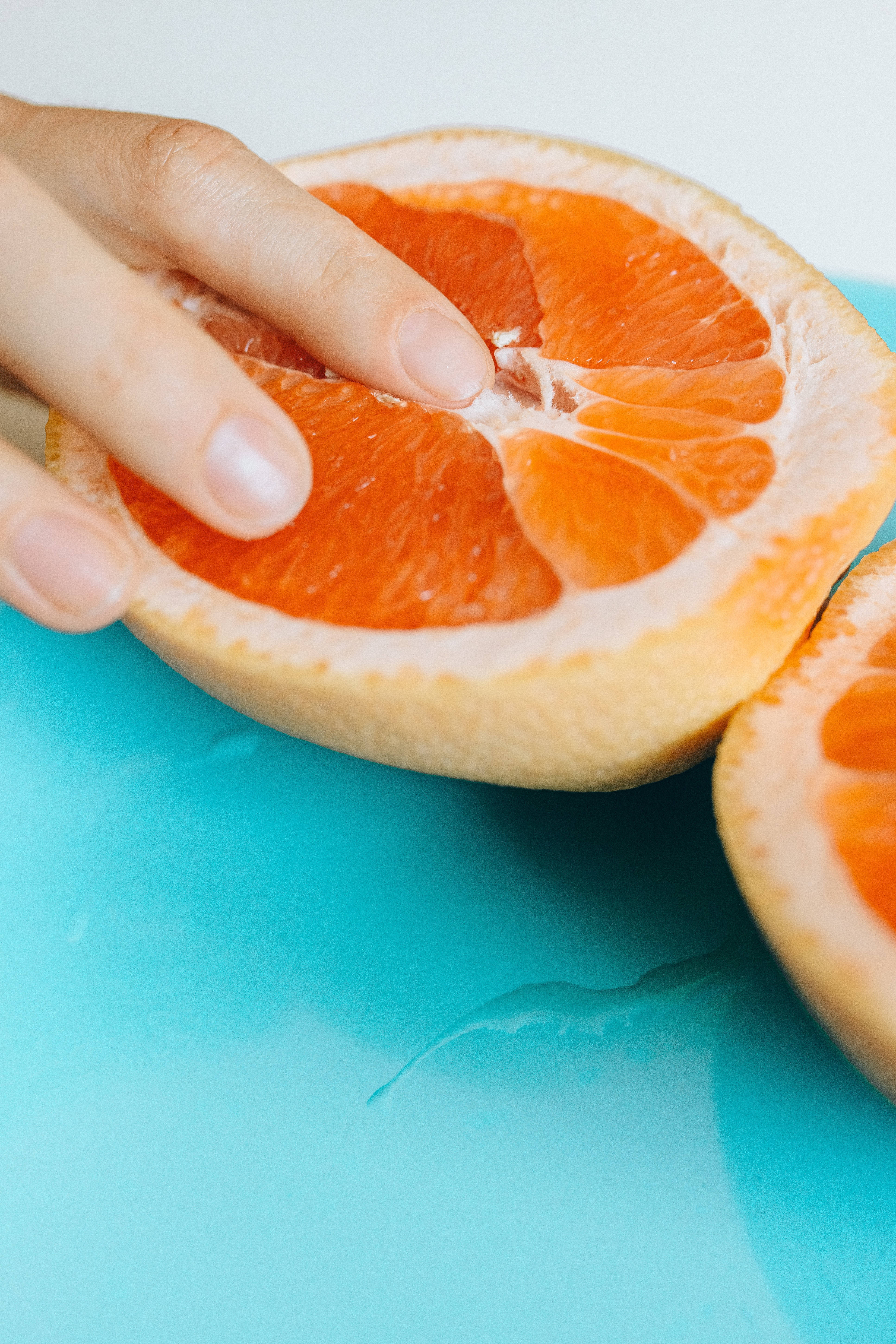 grapefruit, juicy orange grapefruit half, bright turquoise surface, 5K Phone Wallpaper