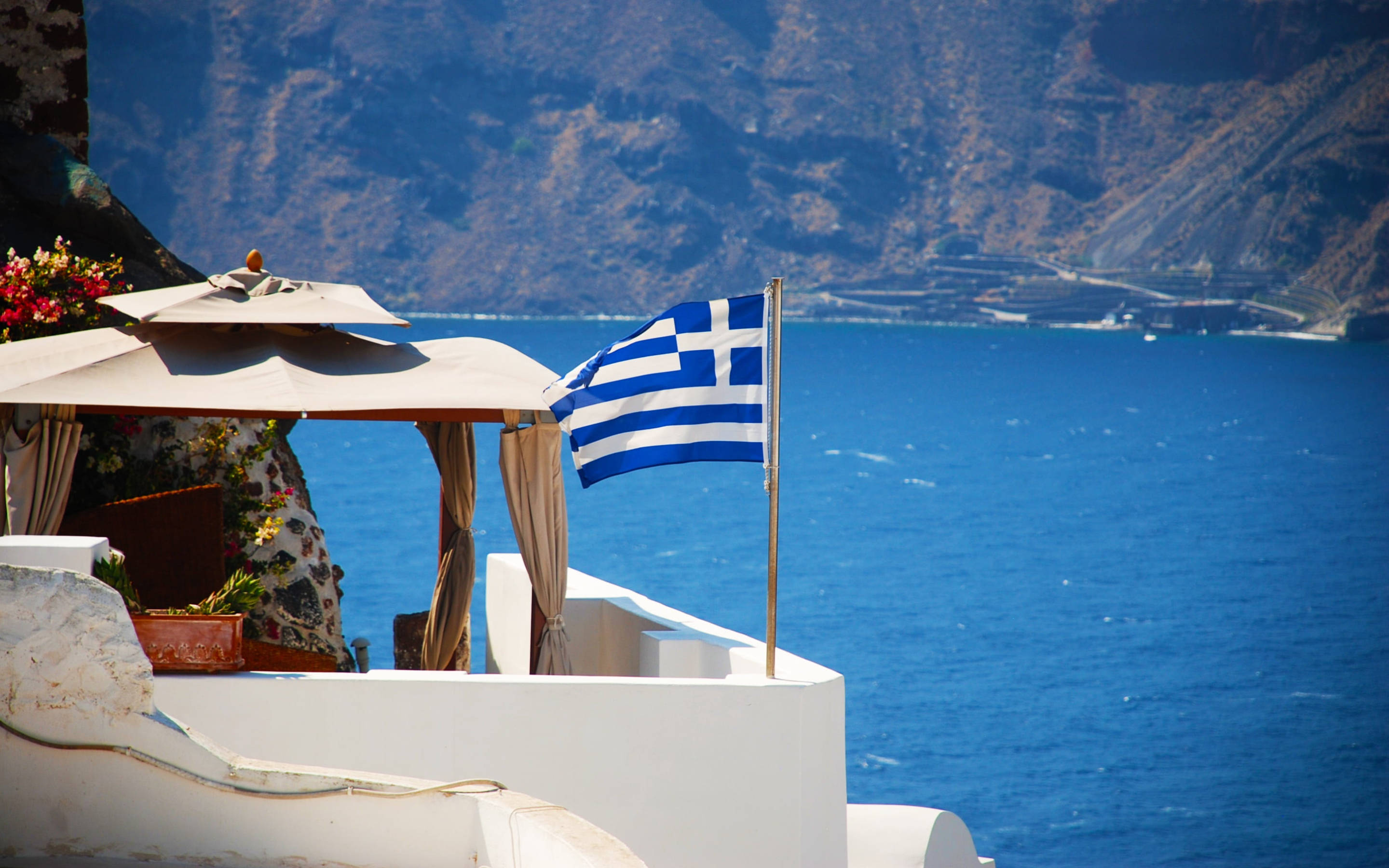 Greek flag, white cliffside terrace, deep blue Aegean Sea, 2K Desktop Wallpaper
