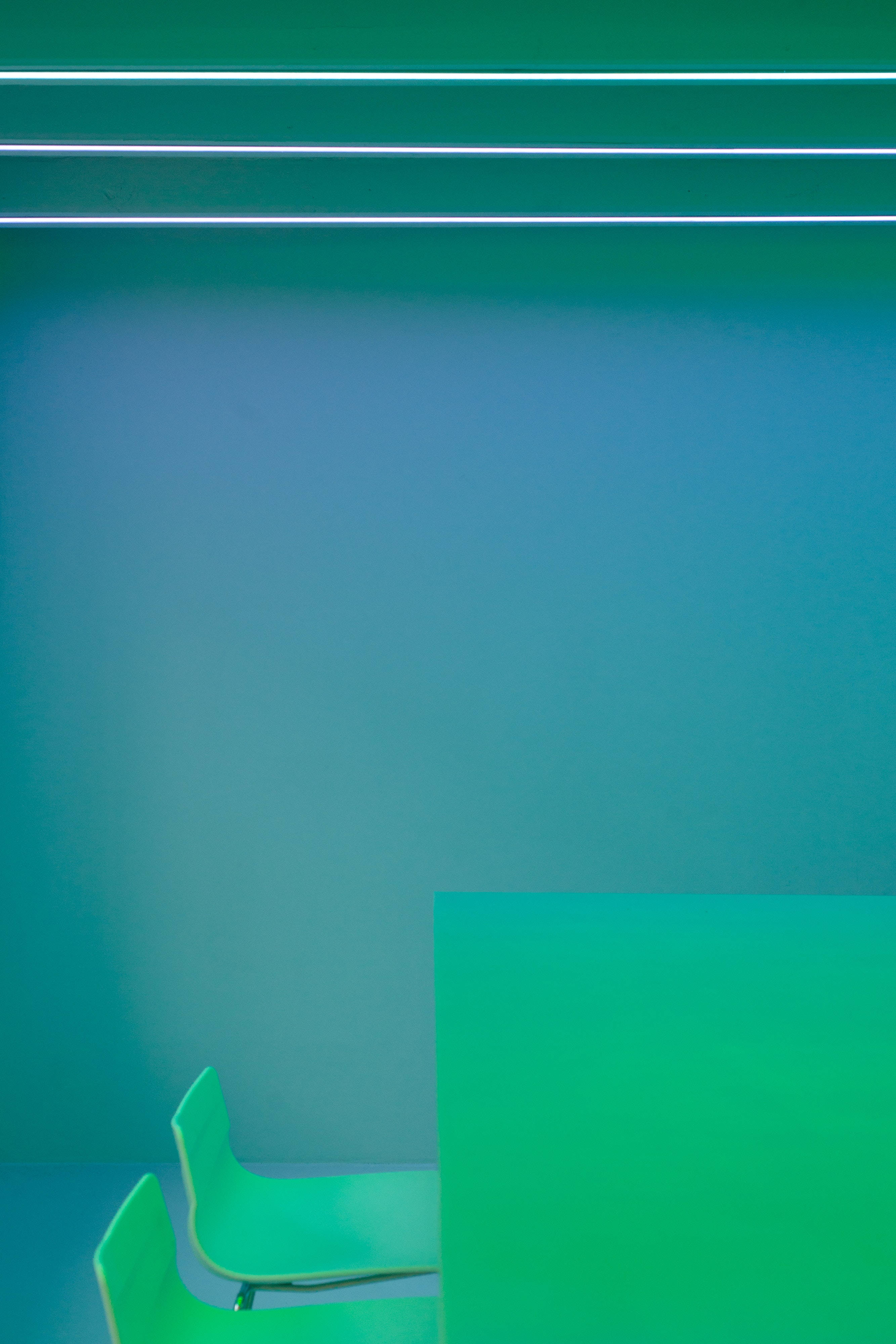 glowing green chairs, gradient teal walls, bright overhead lights, 4K Phone Wallpaper