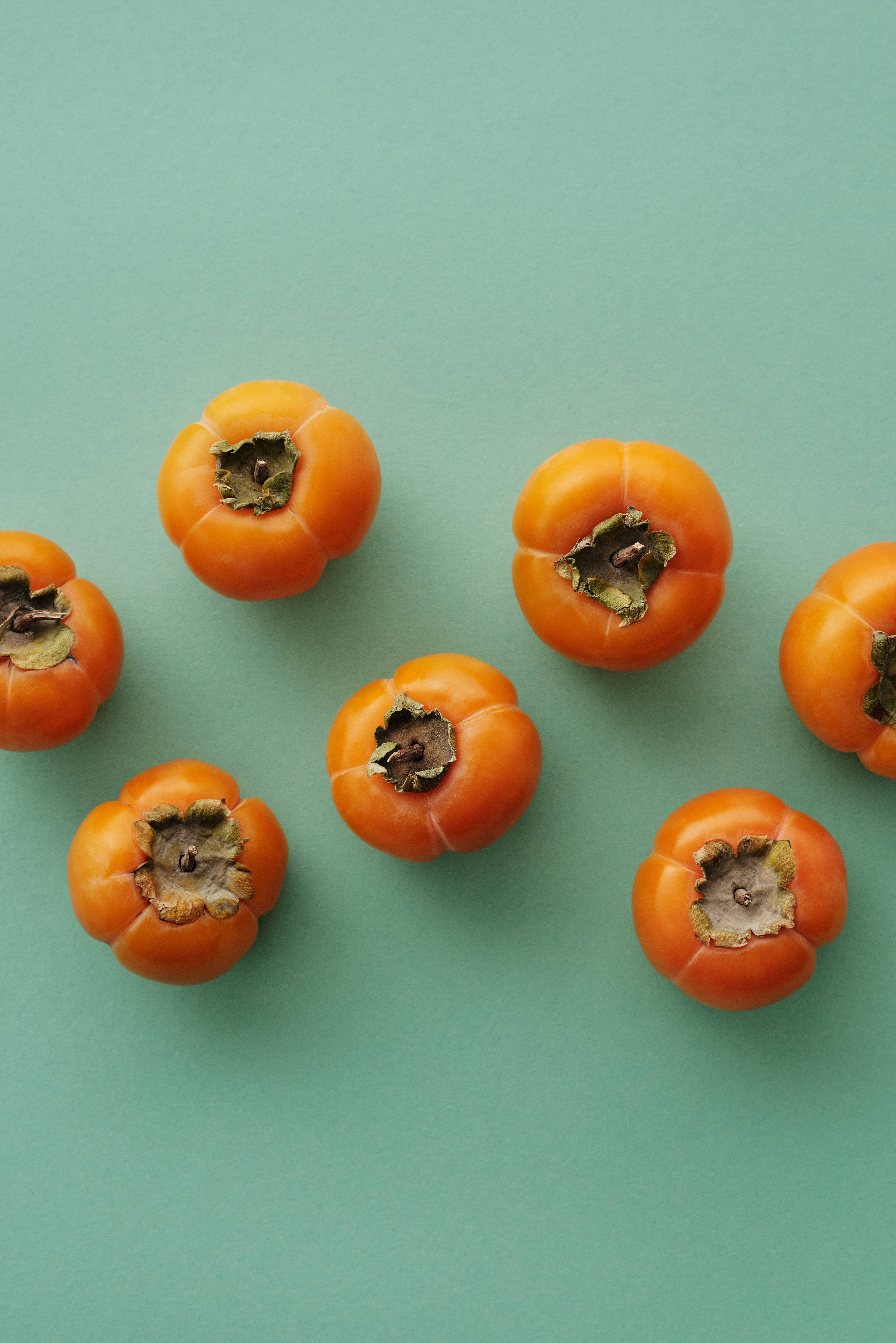 persimmon fruit, teal background, flat lay composition, 5K Phone Wallpaper