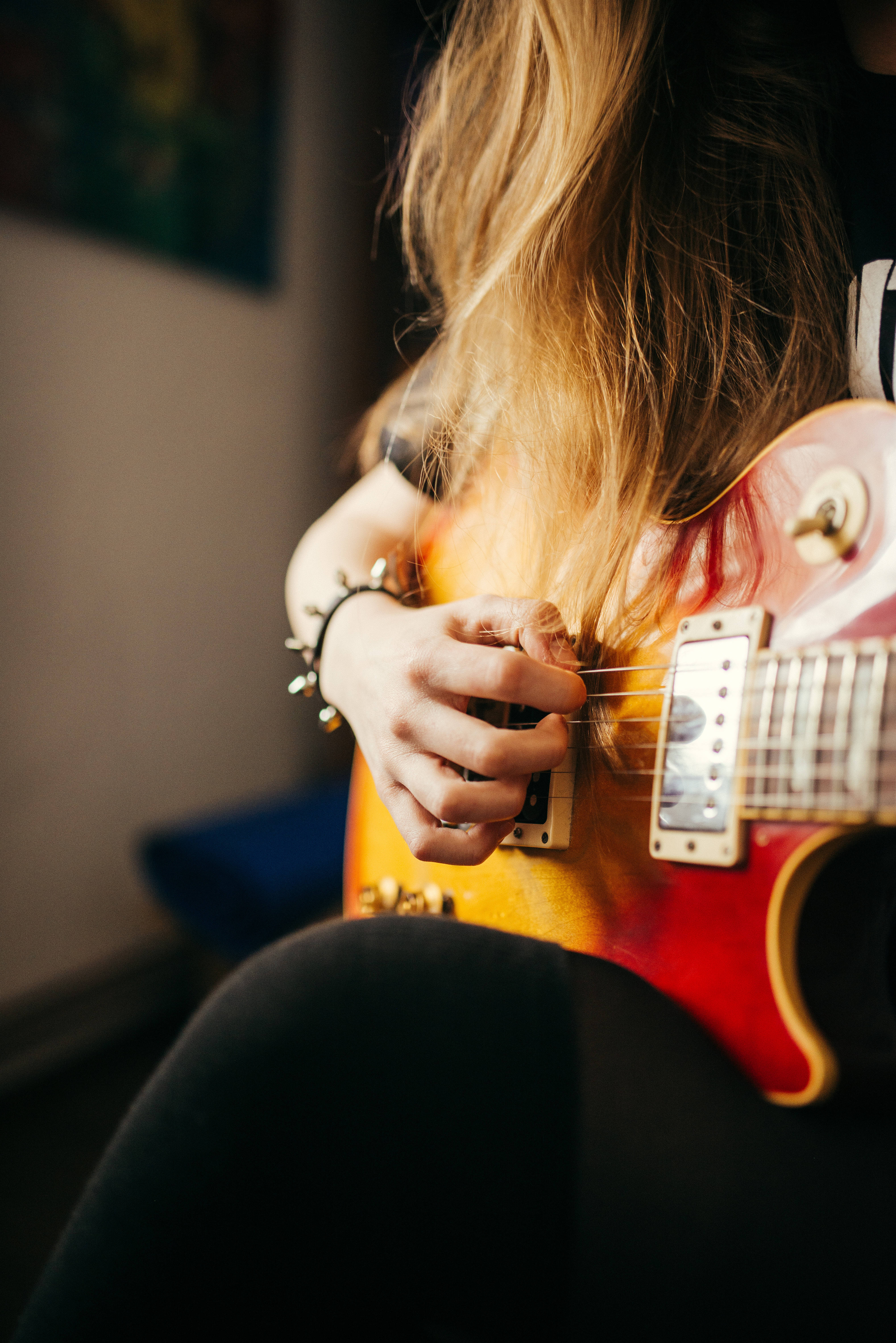 sunburst electric guitar, long blonde hair, warmly lit indoor setting, 5K Phone Wallpaper