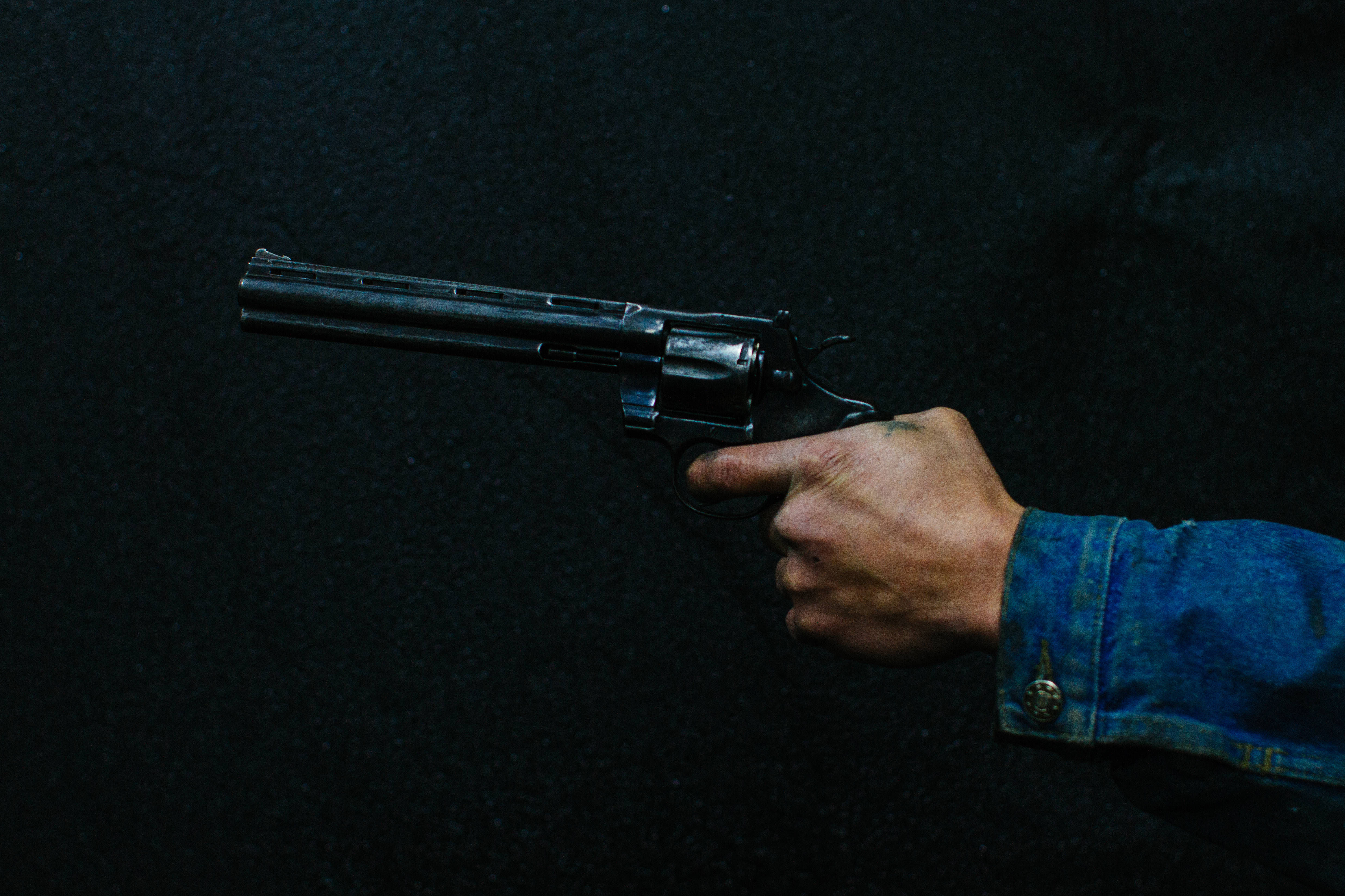 black revolver gun, denim sleeve, dark textured background, 4K Desktop Wallpaper