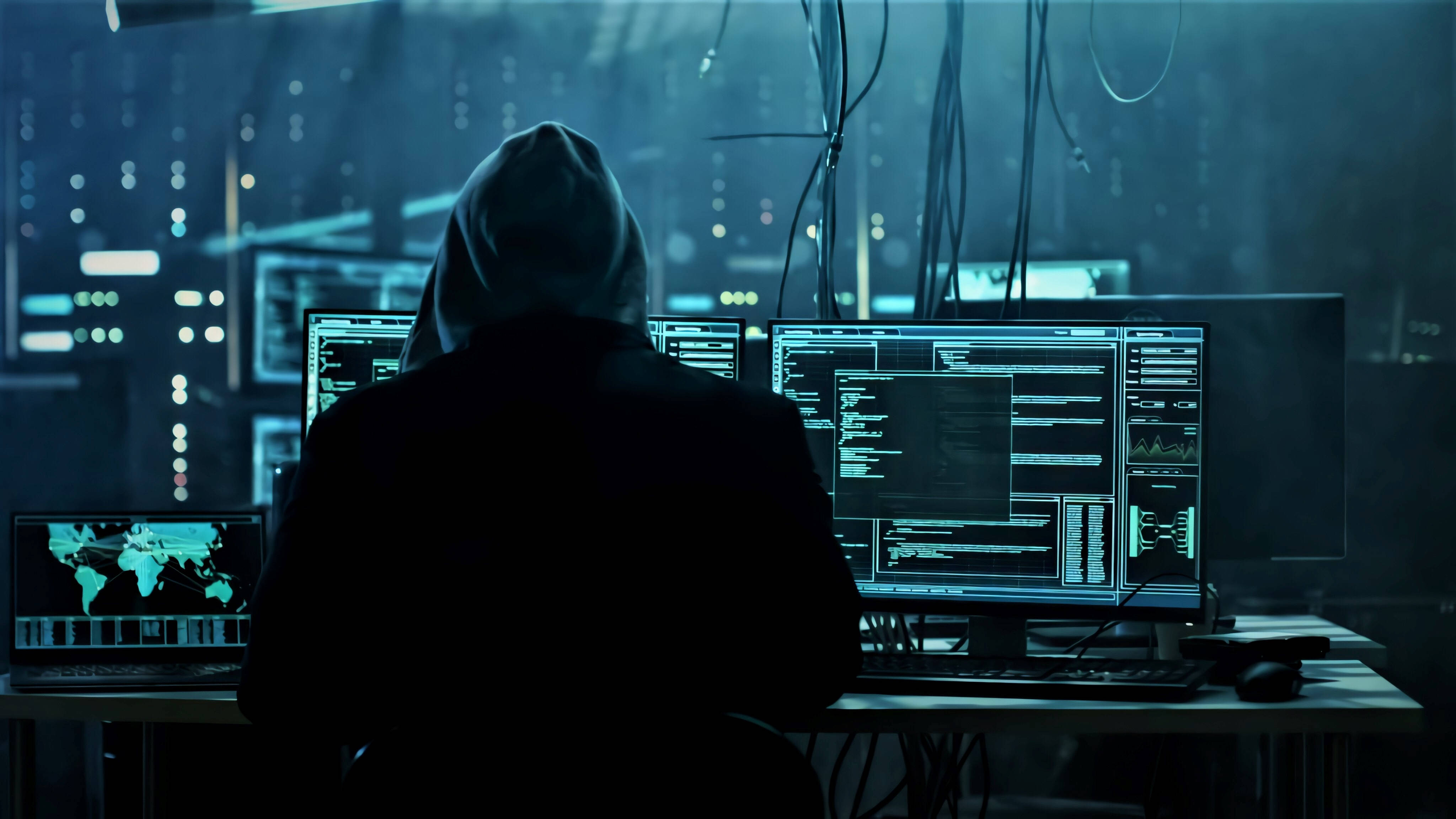 hooded figure, cluttered desk, glowing computer screens, 4K Desktop Wallpaper