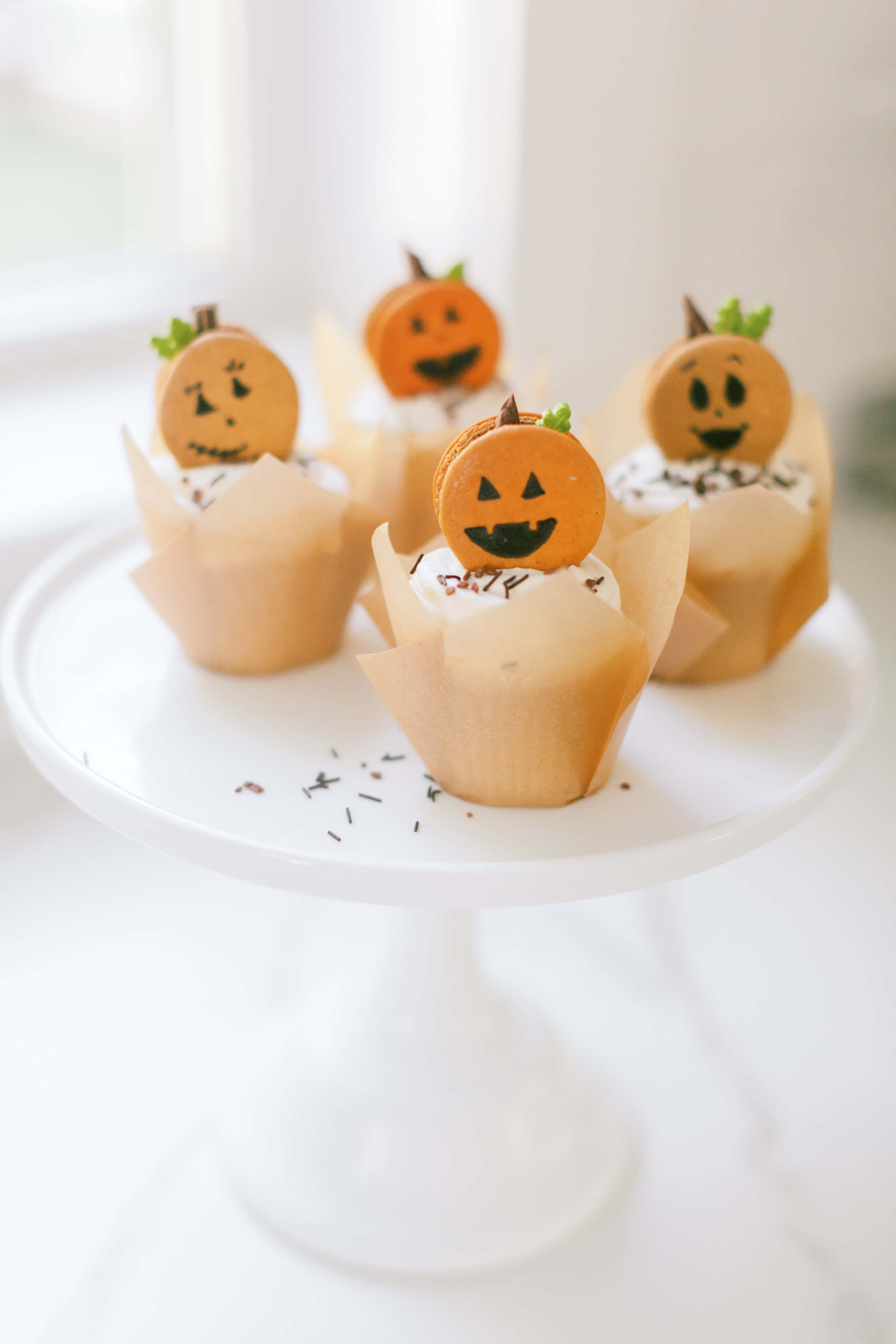 Halloween-themed cupcakes, orange pumpkin macaron toppers, white cake stand, 4K Phone Wallpaper