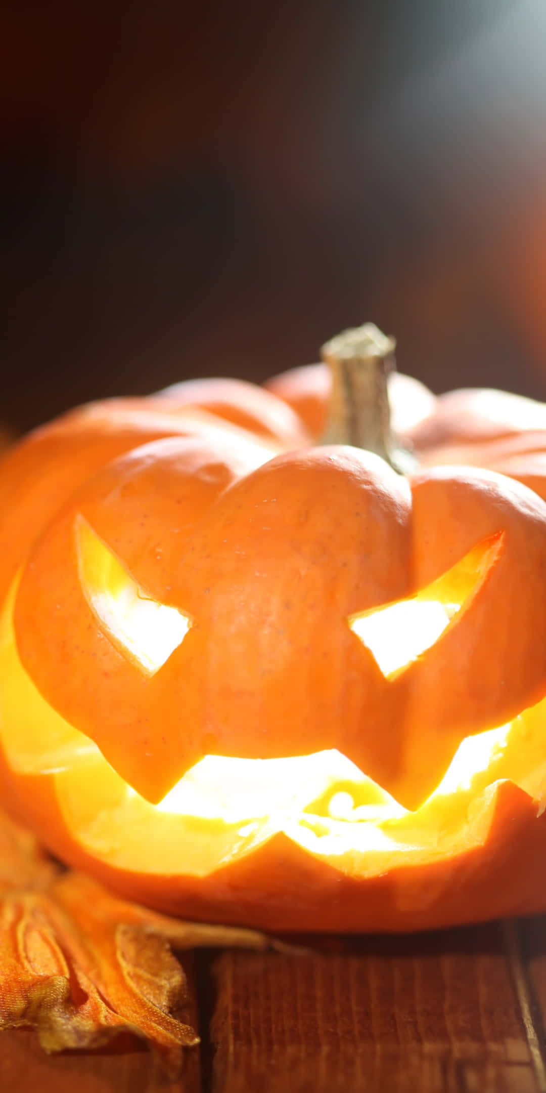 glowing orange jack o lantern pumpkin, carved menacing face, wooden table, Full HD Phone Wallpaper