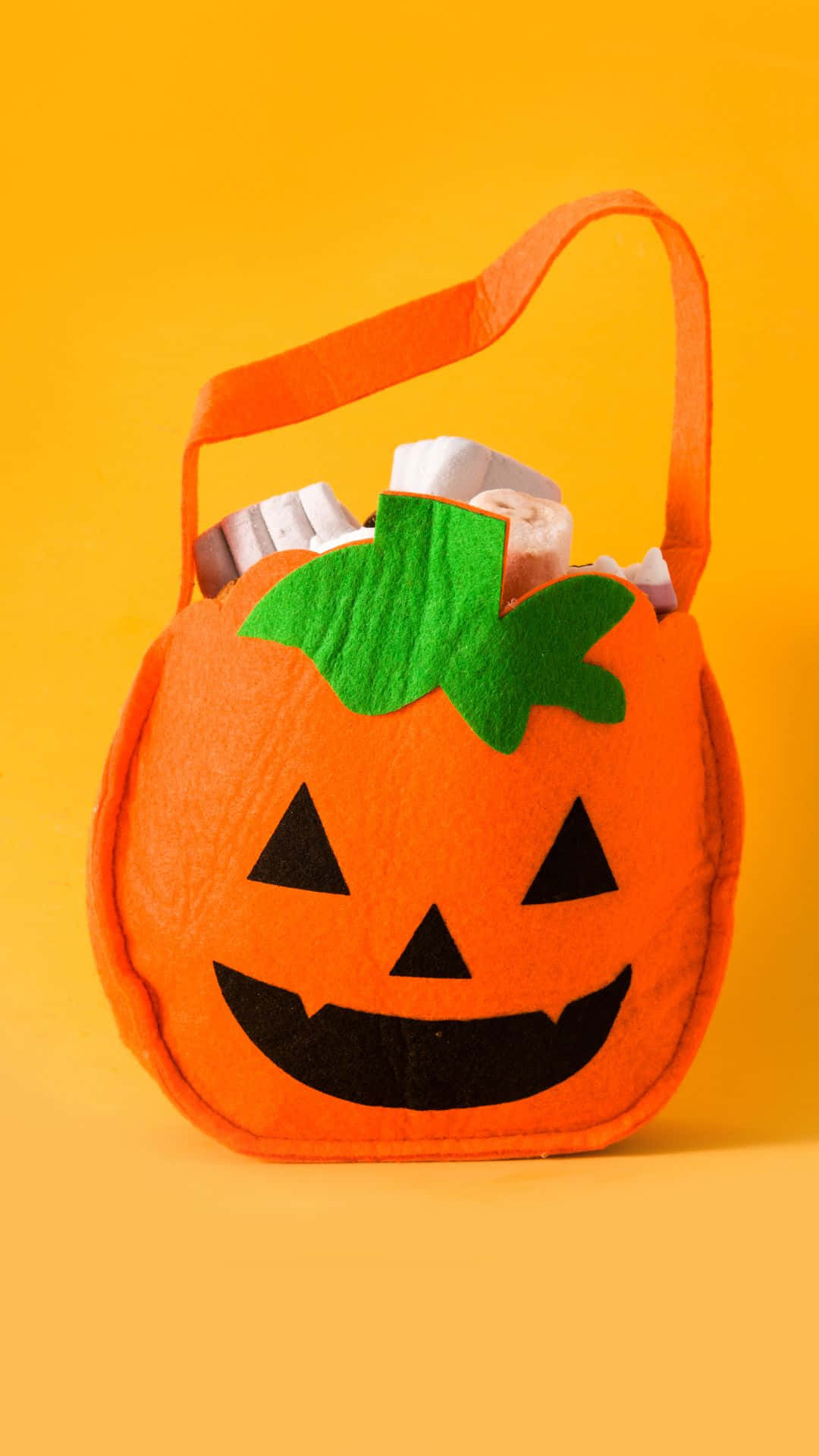 orange felt pumpkin-shaped Halloween candy bag, green stem, black jack-o-lantern face, Full HD Phone Wallpaper
