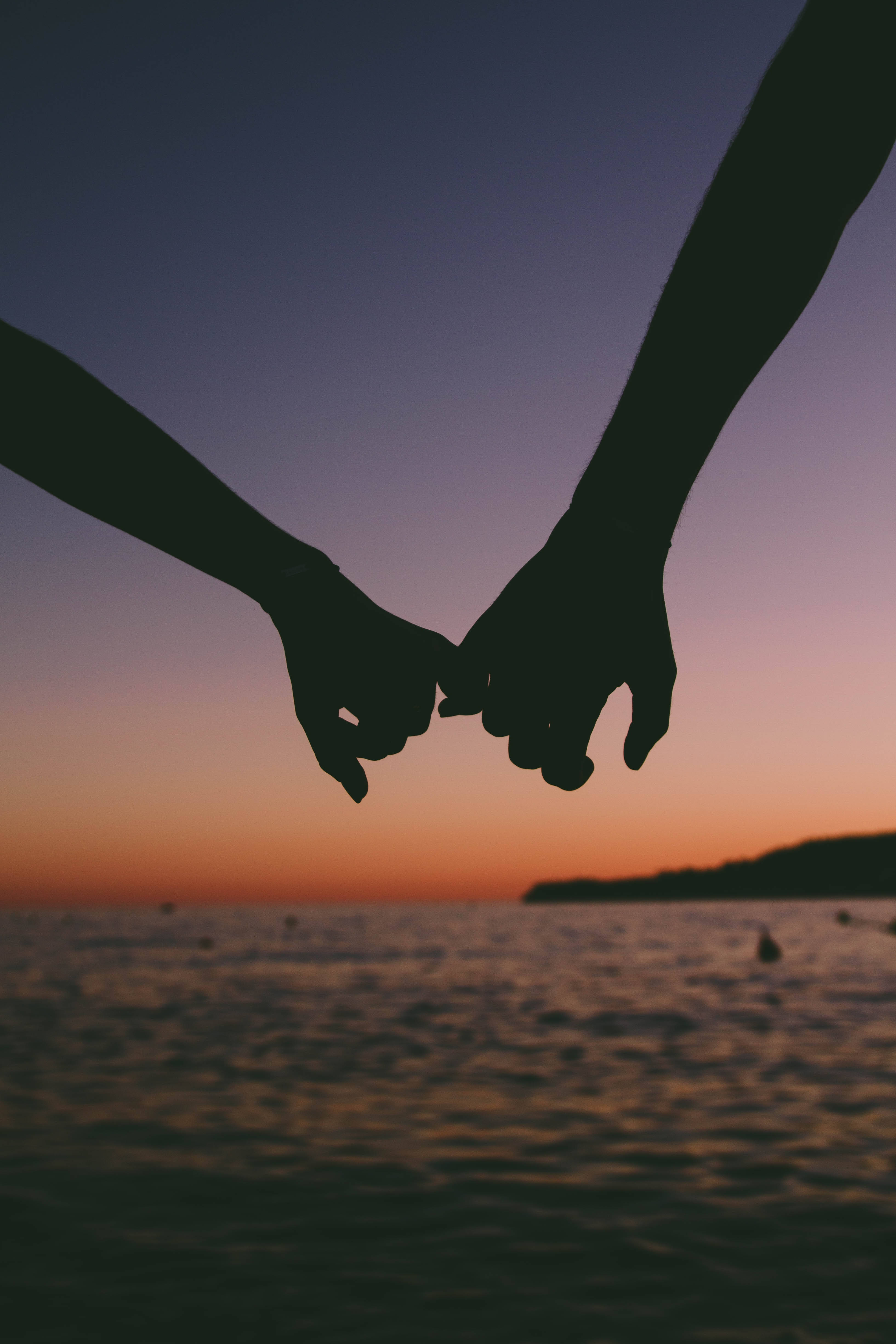 silhouetted hands, vibrant sunset, calm ocean waters, 4K Phone Wallpaper