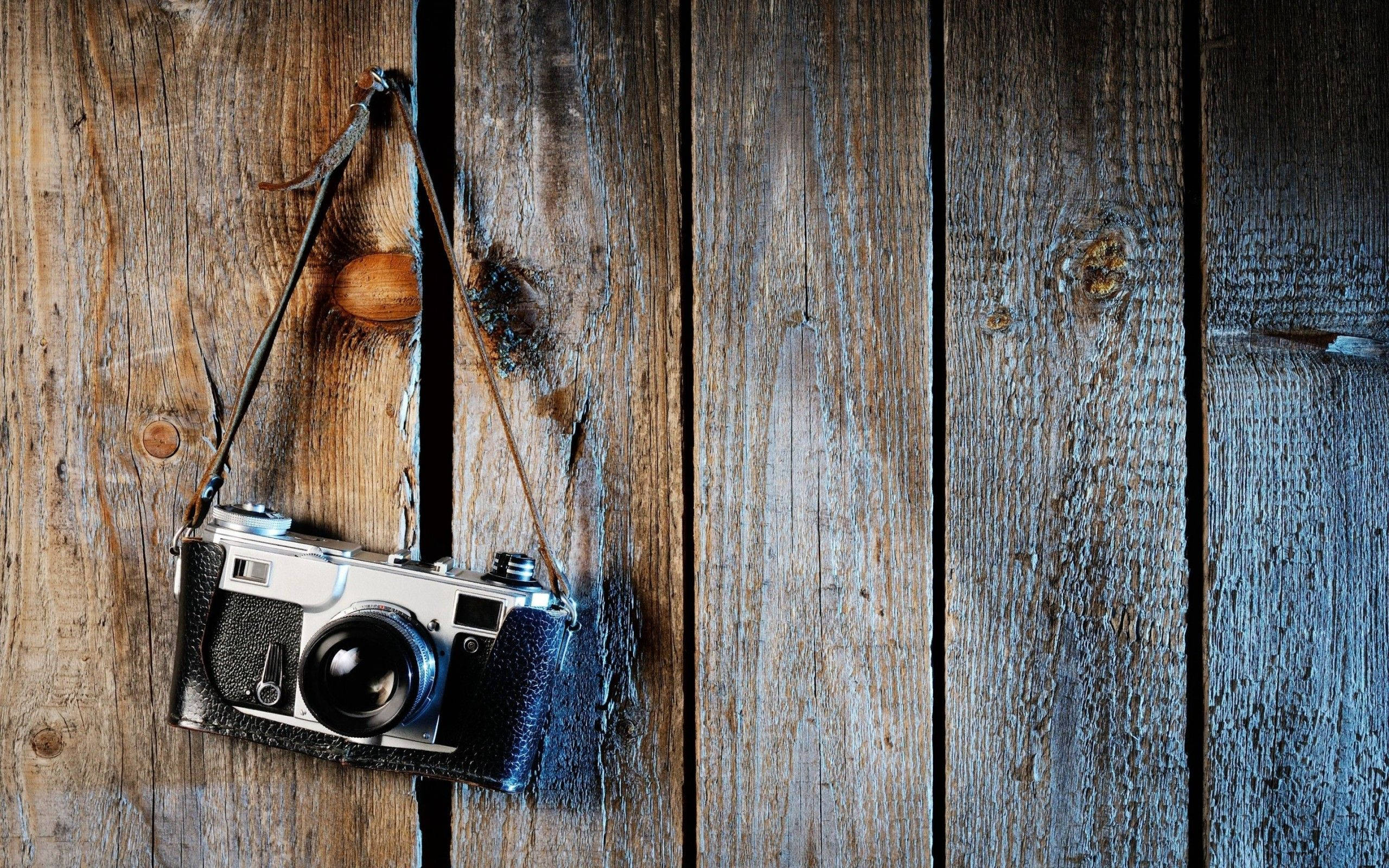 classic hanging film camera, vintage film camera, weathered wooden planks, 2K Desktop Wallpaper