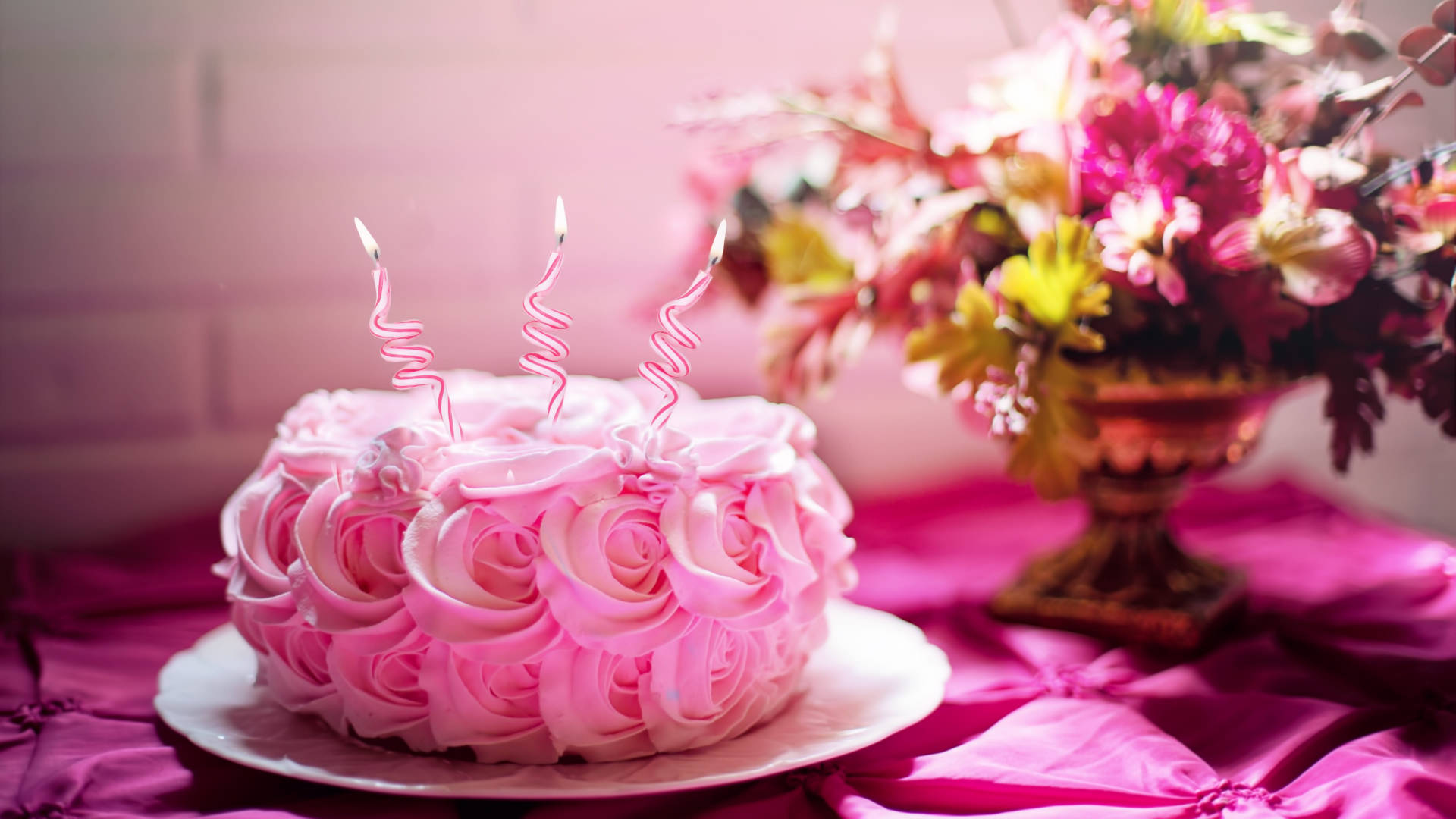 pink rose-shaped cake, three lit spiral candles, floral arrangement, Full HD Desktop Wallpaper