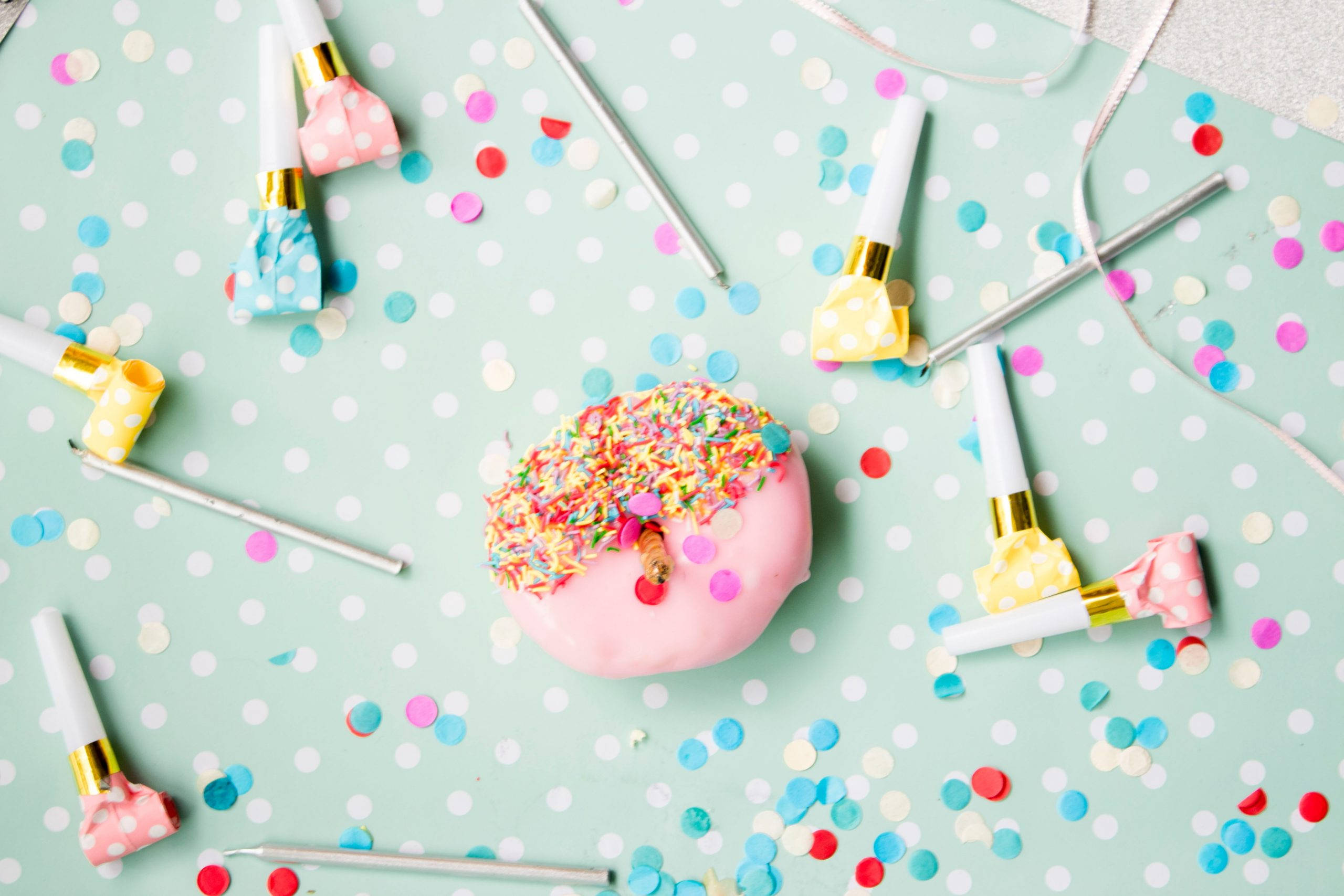 pink frosted donut, colorful sprinkles, mint green polka dot surface, 2K Desktop Wallpaper