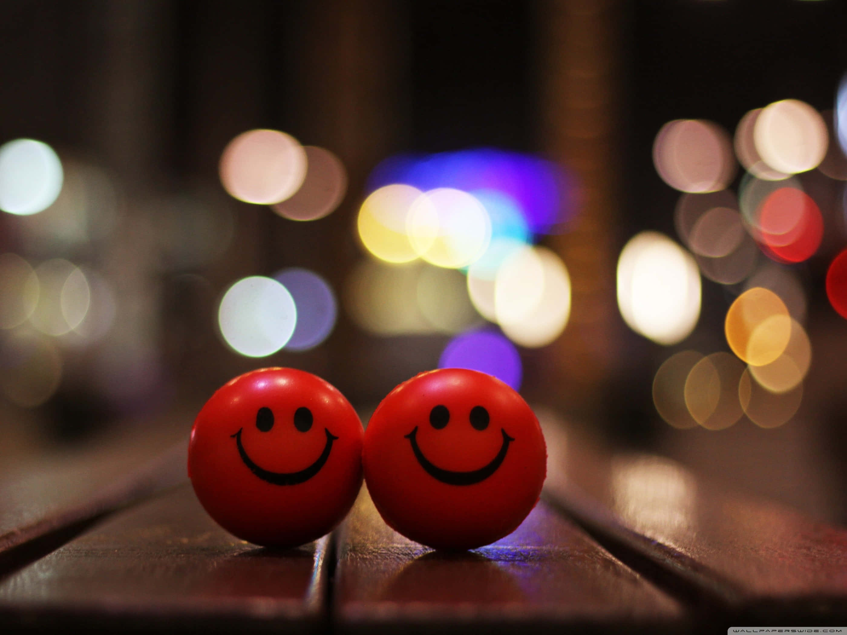 red smiley balls, wooden table, colorful bokeh lights, 2K Desktop Wallpaper
