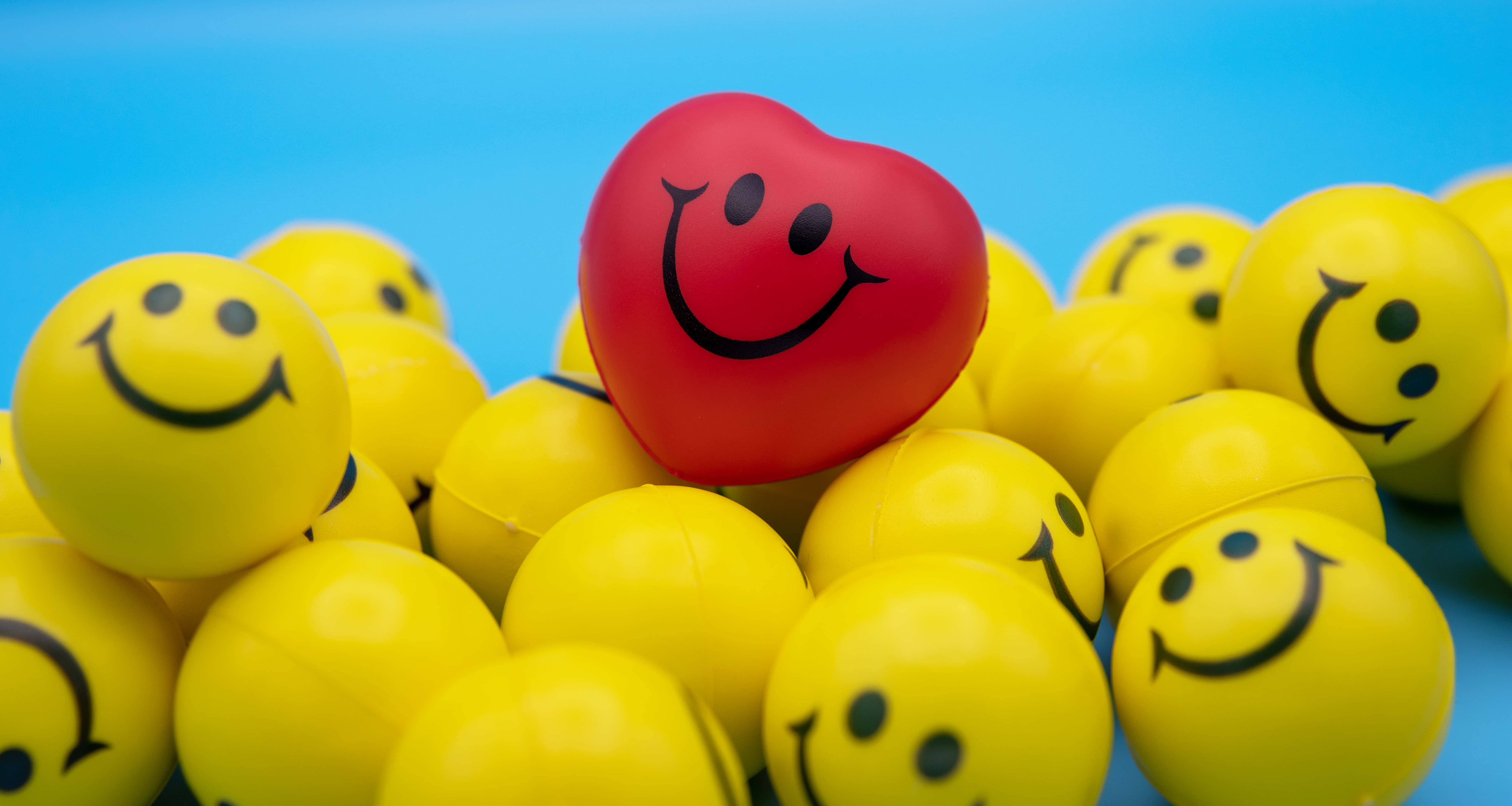 red heart-shaped smiley ball, yellow smiley balls, bright blue background, 5K Desktop Wallpaper