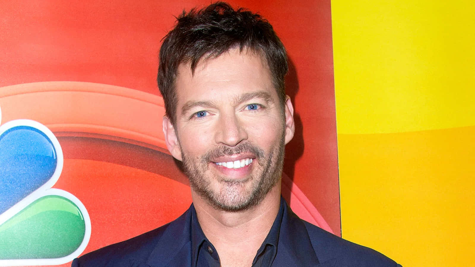 Harry Connick Jr, dark suit, vibrant red yellow and blue NBC logo backdrop, HD Desktop Wallpaper