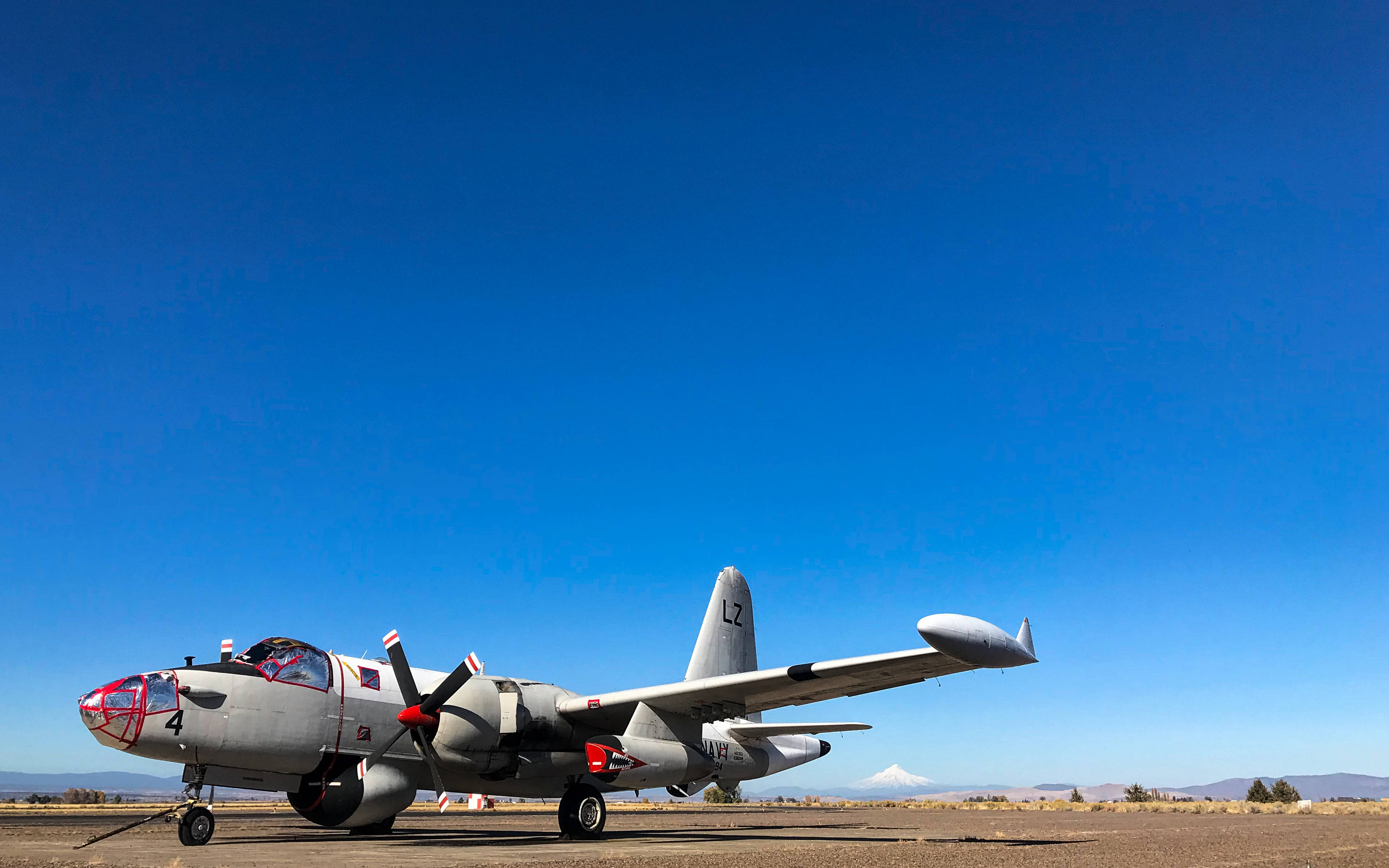 vintage military propeller plane, desert tarmac, vast clear blue sky, 2K Desktop Wallpaper