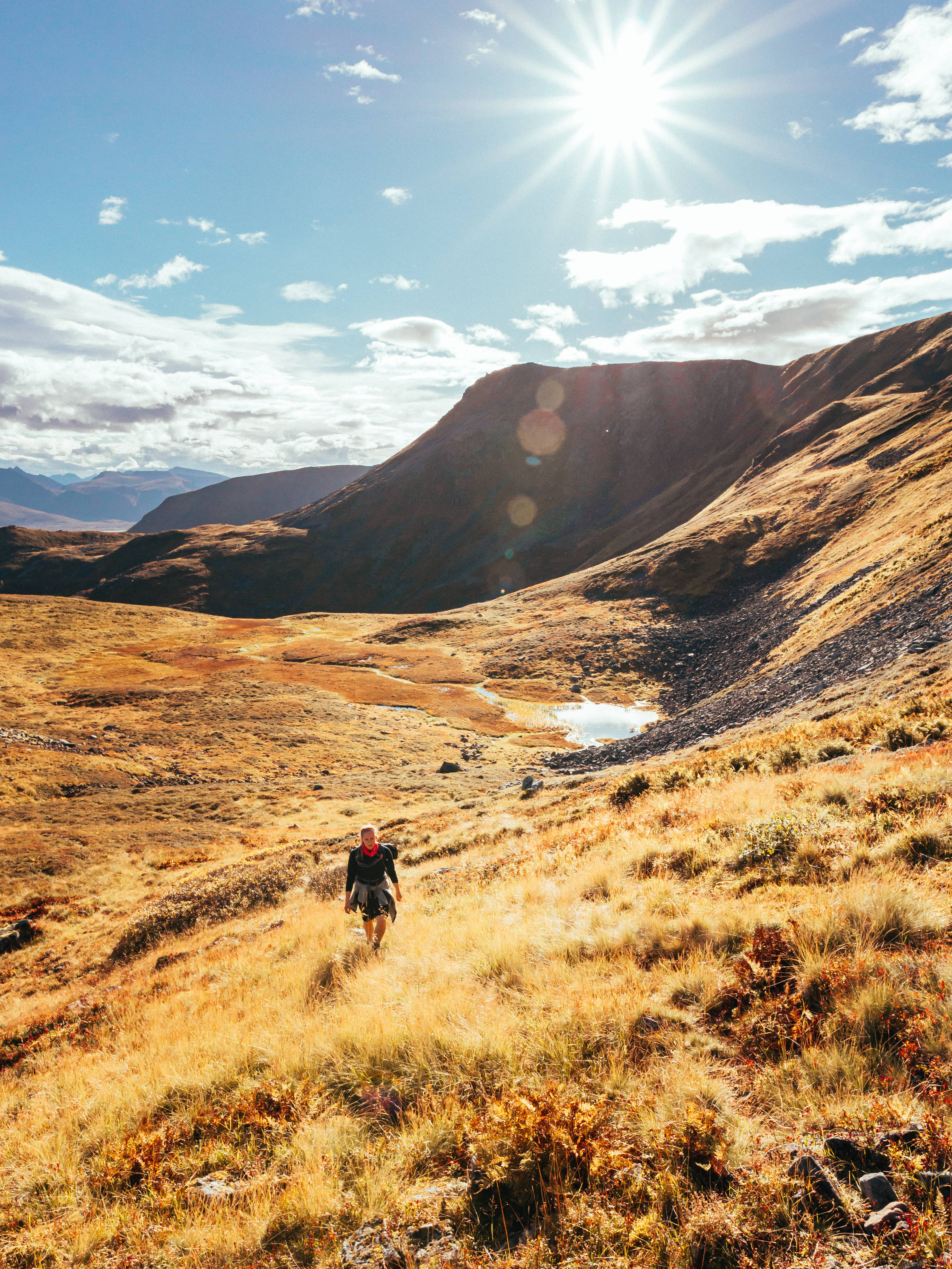lone hiker, sun-drenched golden valley, rugged mountains, 5K Phone Wallpaper