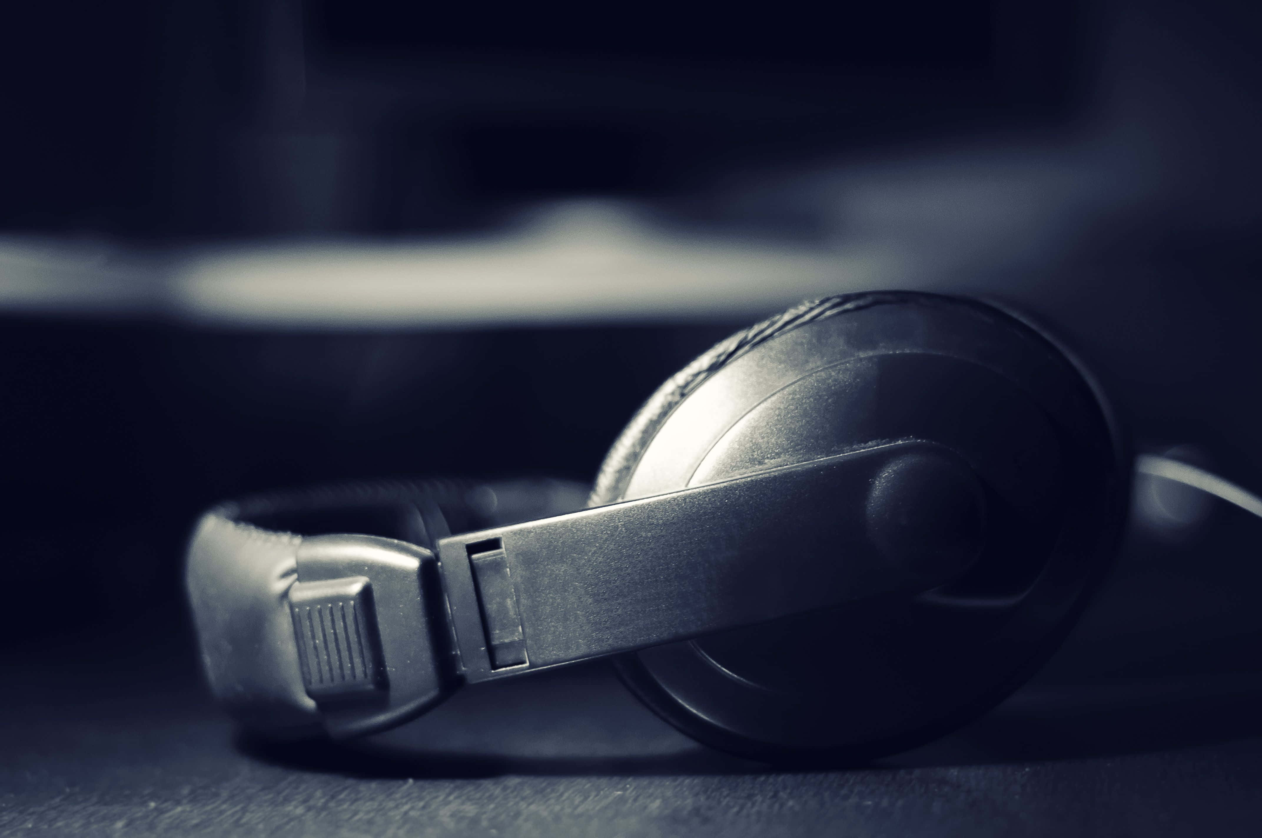 black over-ear headphones, dark surface, shallow depth of field, 4K Desktop Wallpaper