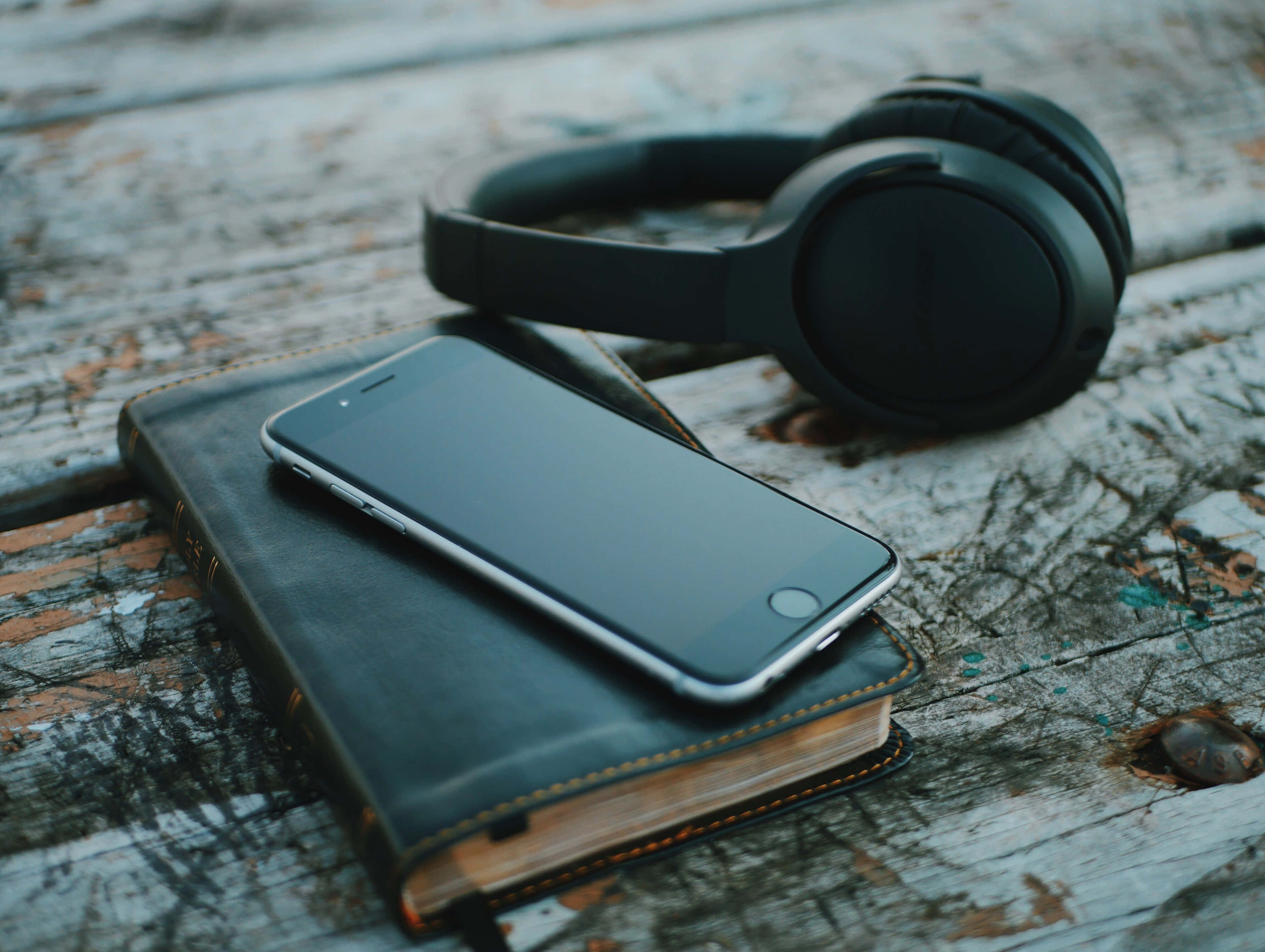 black headphones, leather-bound book, weathered wooden surface, 4K Desktop Wallpaper