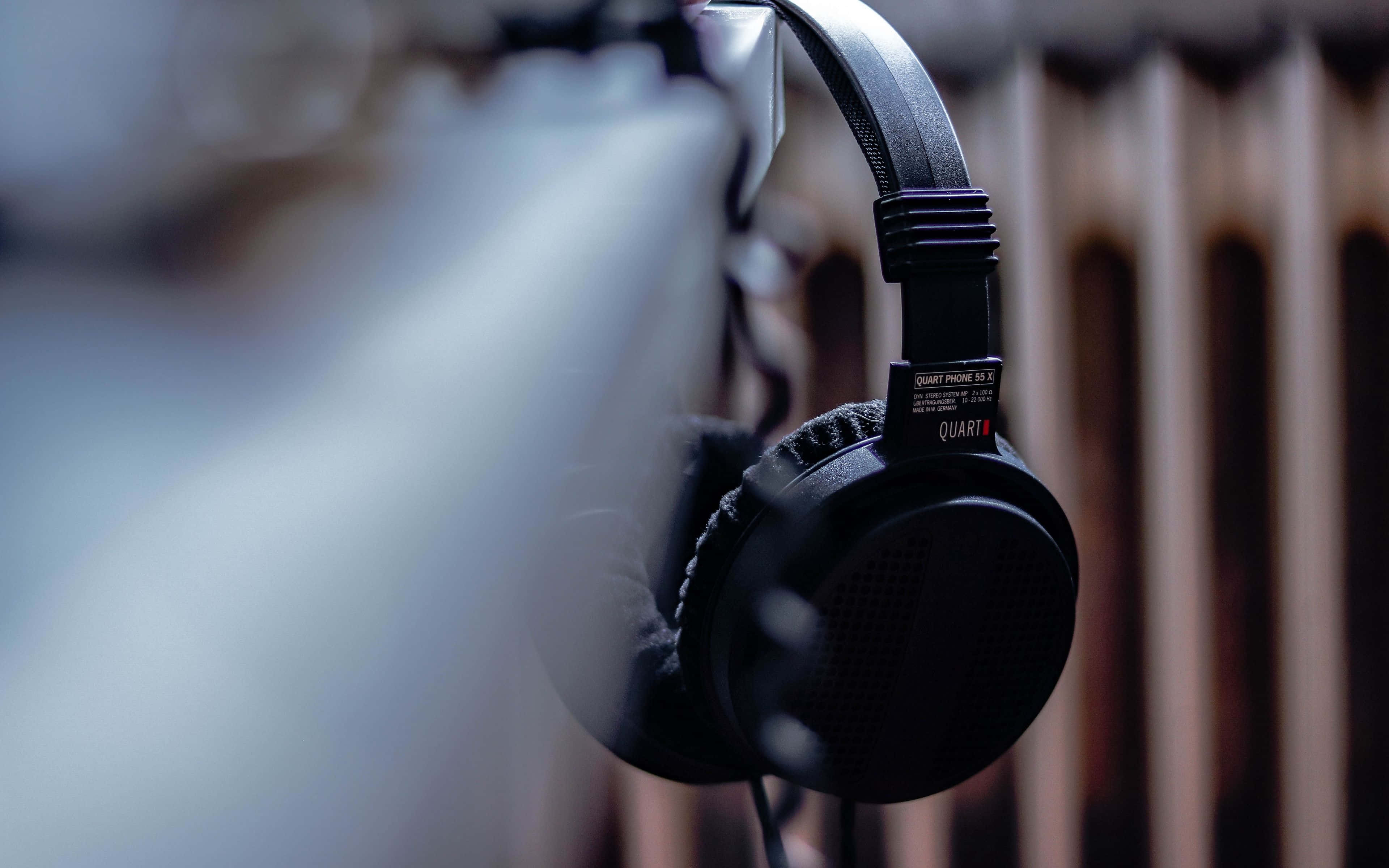 black over-ear headphones, blurred wooden background, soft lighting, 4K Desktop Wallpaper