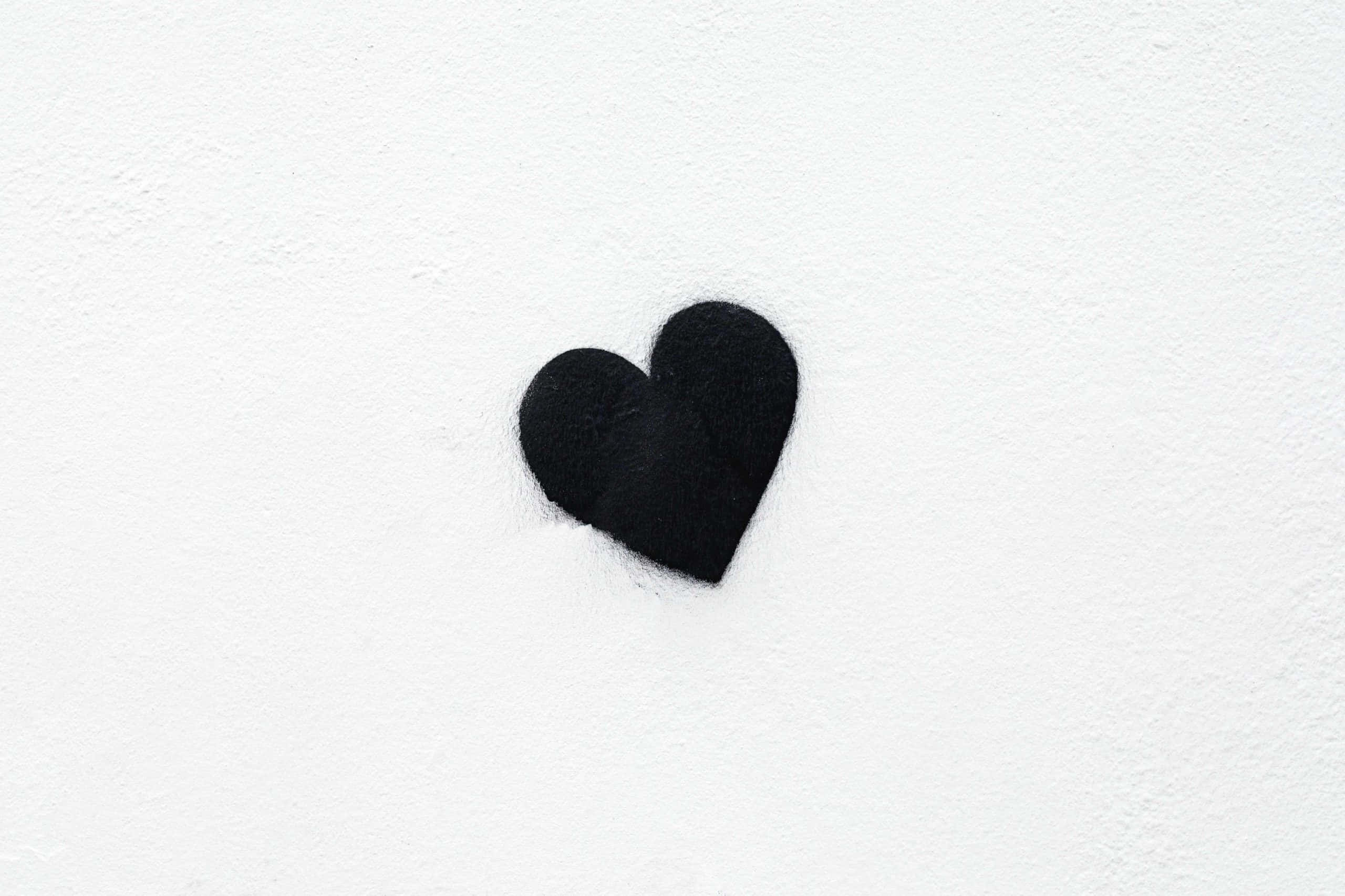 black felt heart, textured white wall surface, white background, 2K Desktop Wallpaper