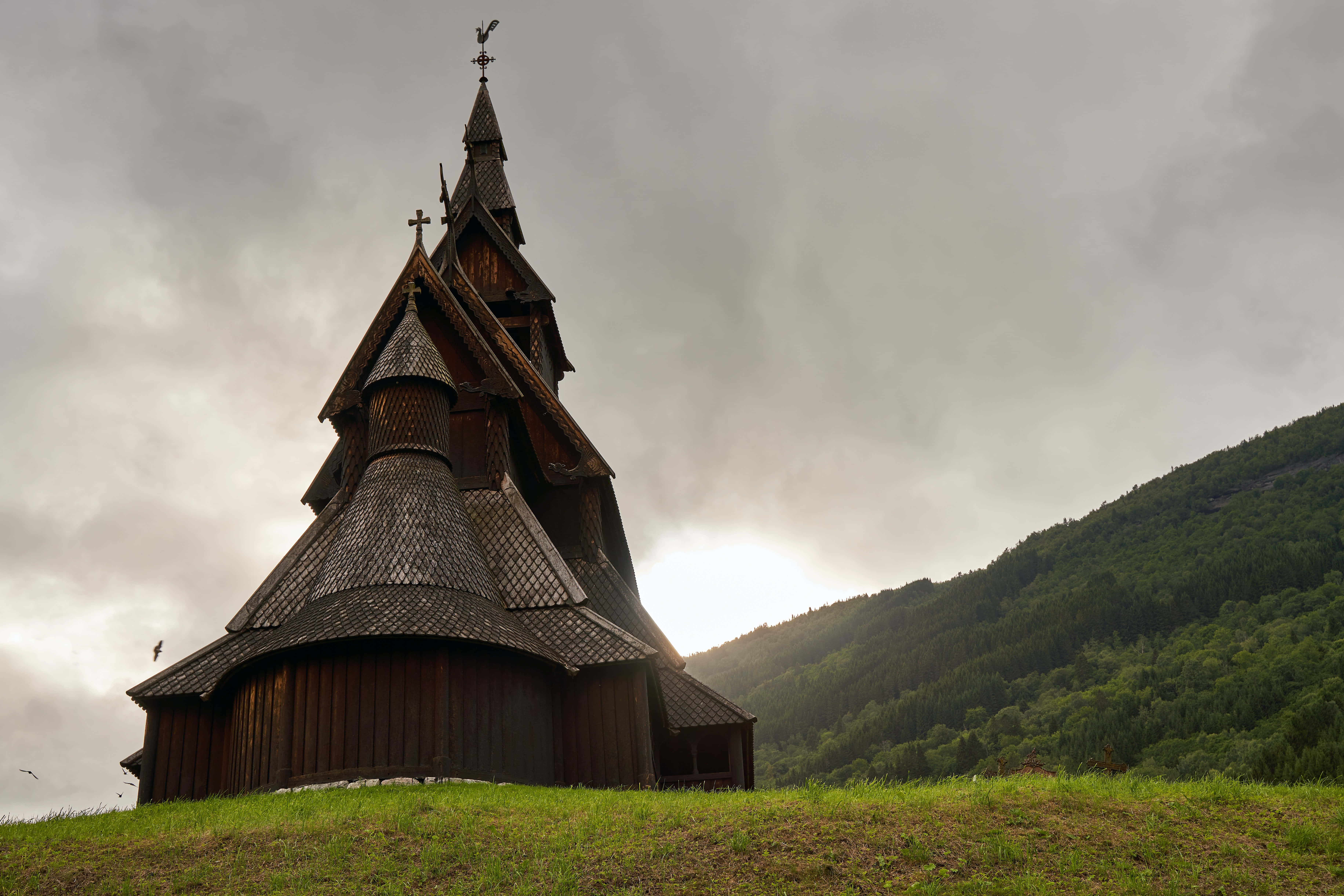 Heddal Stave Church, peeking sun, cloudy sky, 5K Desktop Wallpaper