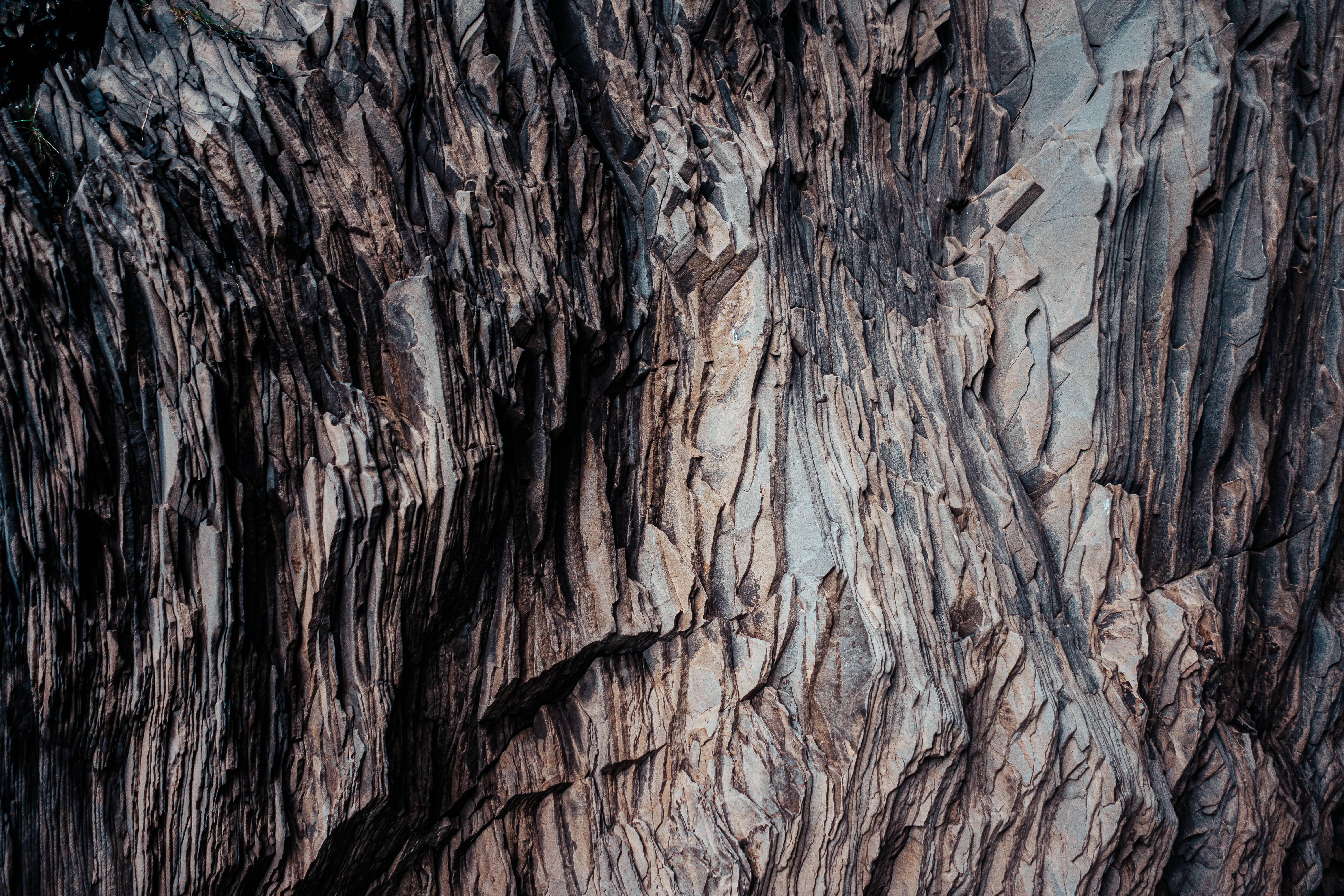 layered dark rock, rugged layered rock formations, deep shadows, 5K Desktop Wallpaper